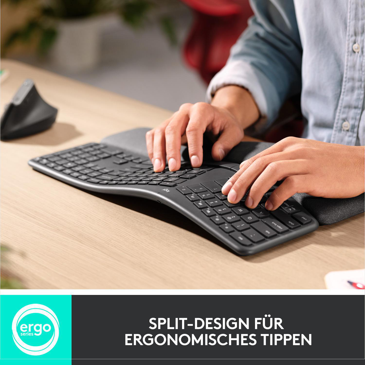 Person tippt auf einer geteilten ergonomischen Tastatur auf einem Holzschreibtisch.