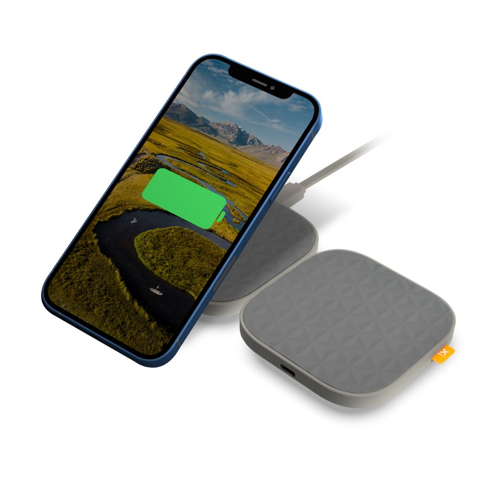 Ein blaues Telefon, das kabellos auf einem grauen Pad geladen wird. Eine Berg- und Flussszene auf dem Bildschirm.