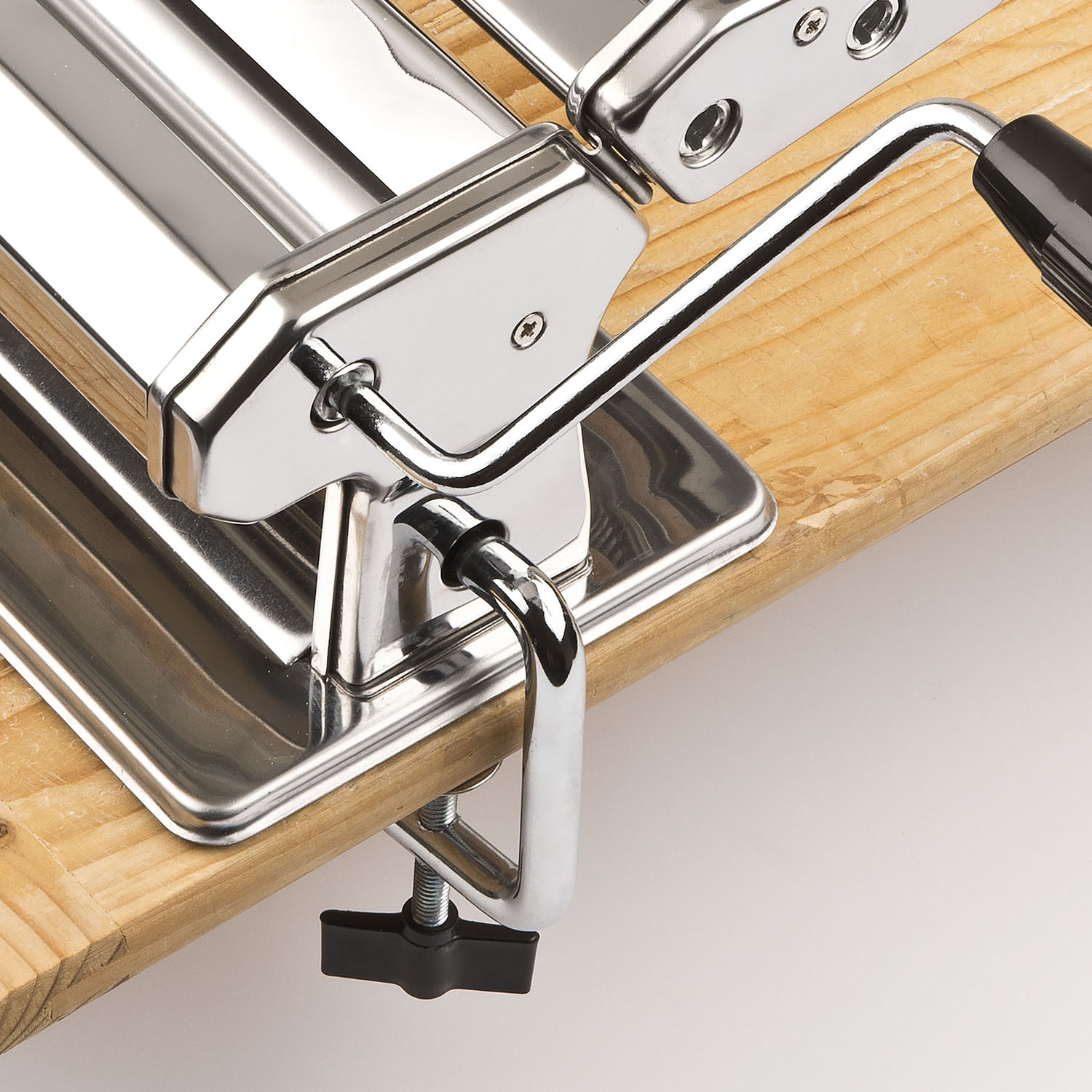Primo piano di una macchina per la pasta. È in acciaio inossidabile su una superficie di legno. Maniglia per l'uso.
