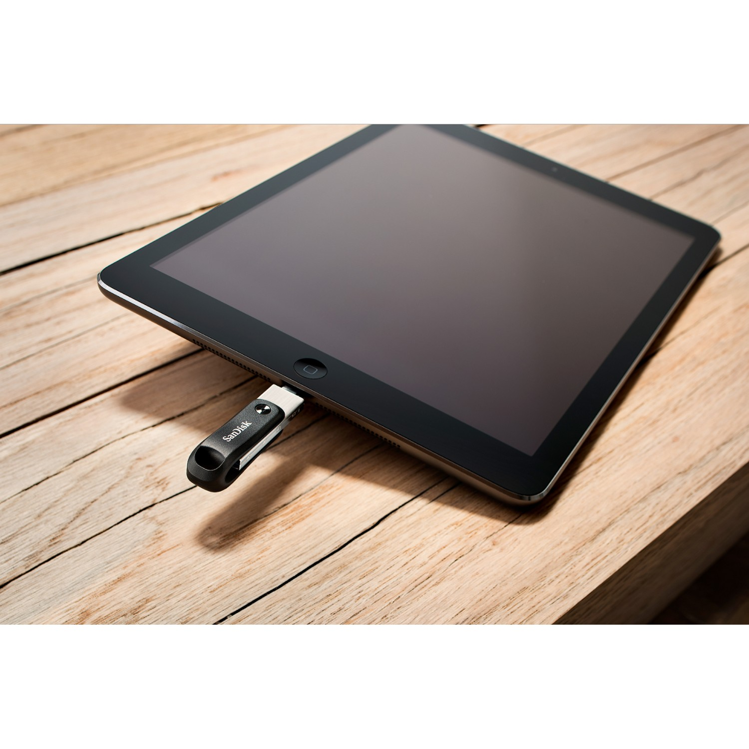 Tableta con una unidad USB insertada. La tableta está sobre una superficie de madera. La unidad USB es negra y plateada.