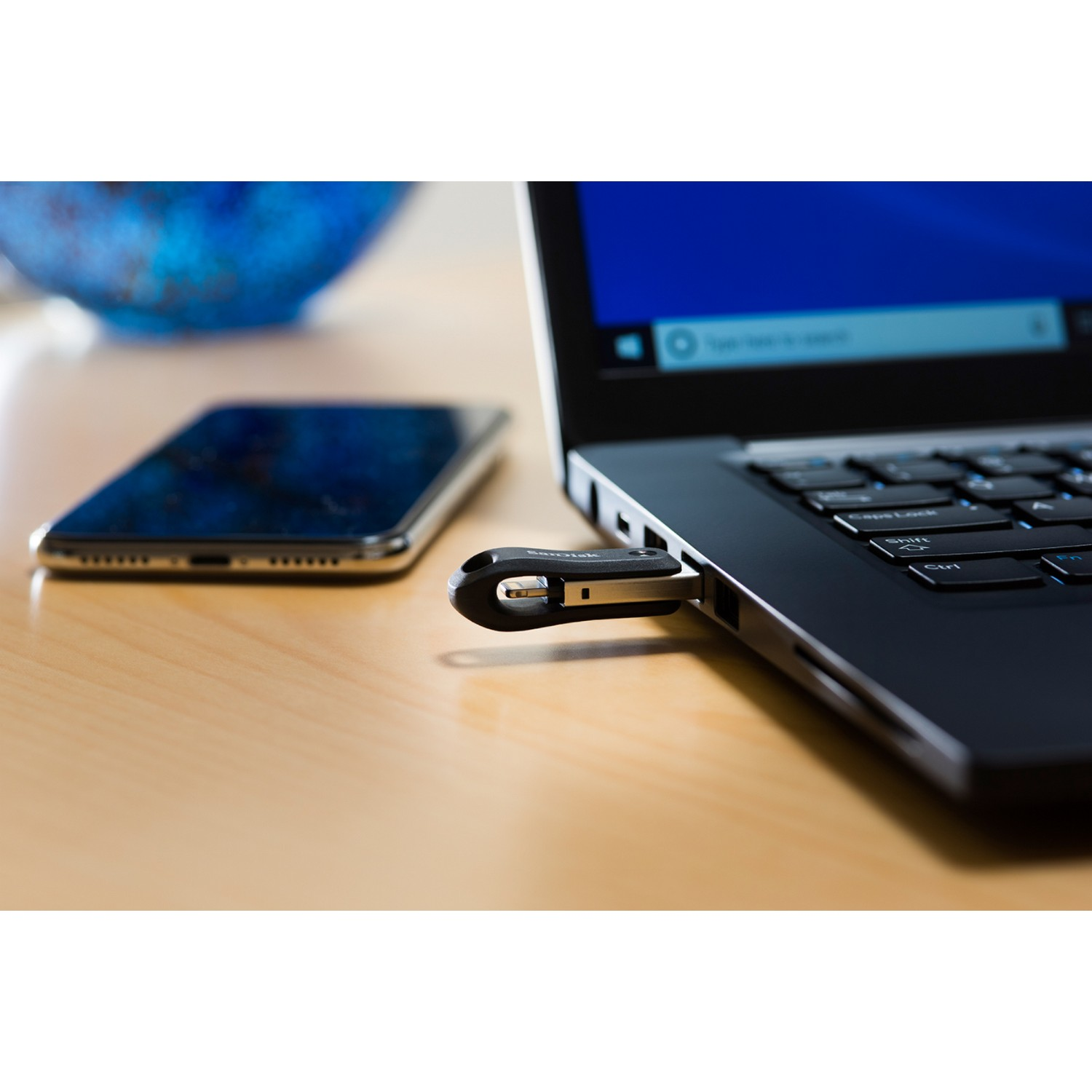 Un smartphone junto a un portátil con una unidad USB.