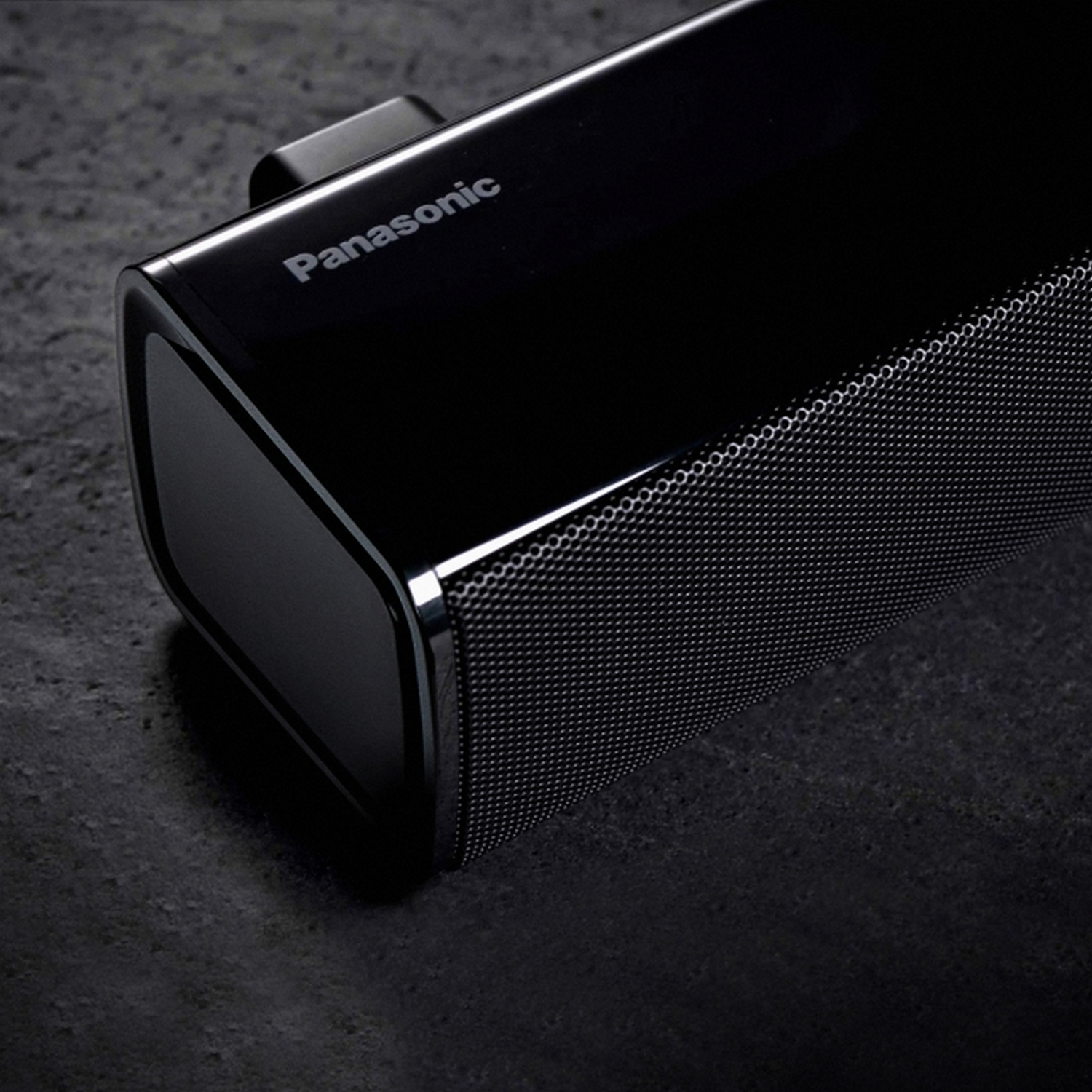 Barra de sonido Panasonic negra sobre superficie oscura. El altavoz tiene frontal de malla y diseño moderno.