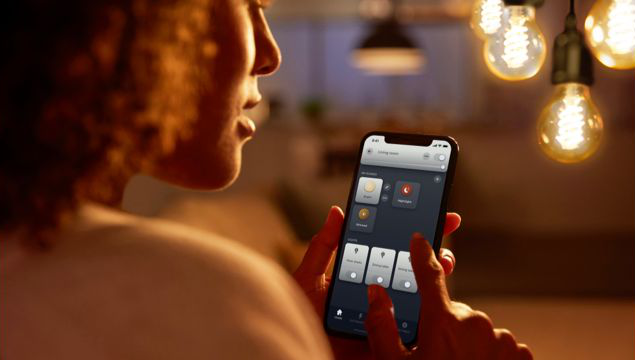 Persona che tiene in mano uno smartphone per controllare le luci intelligenti. Vengono visualizzate varie impostazioni.