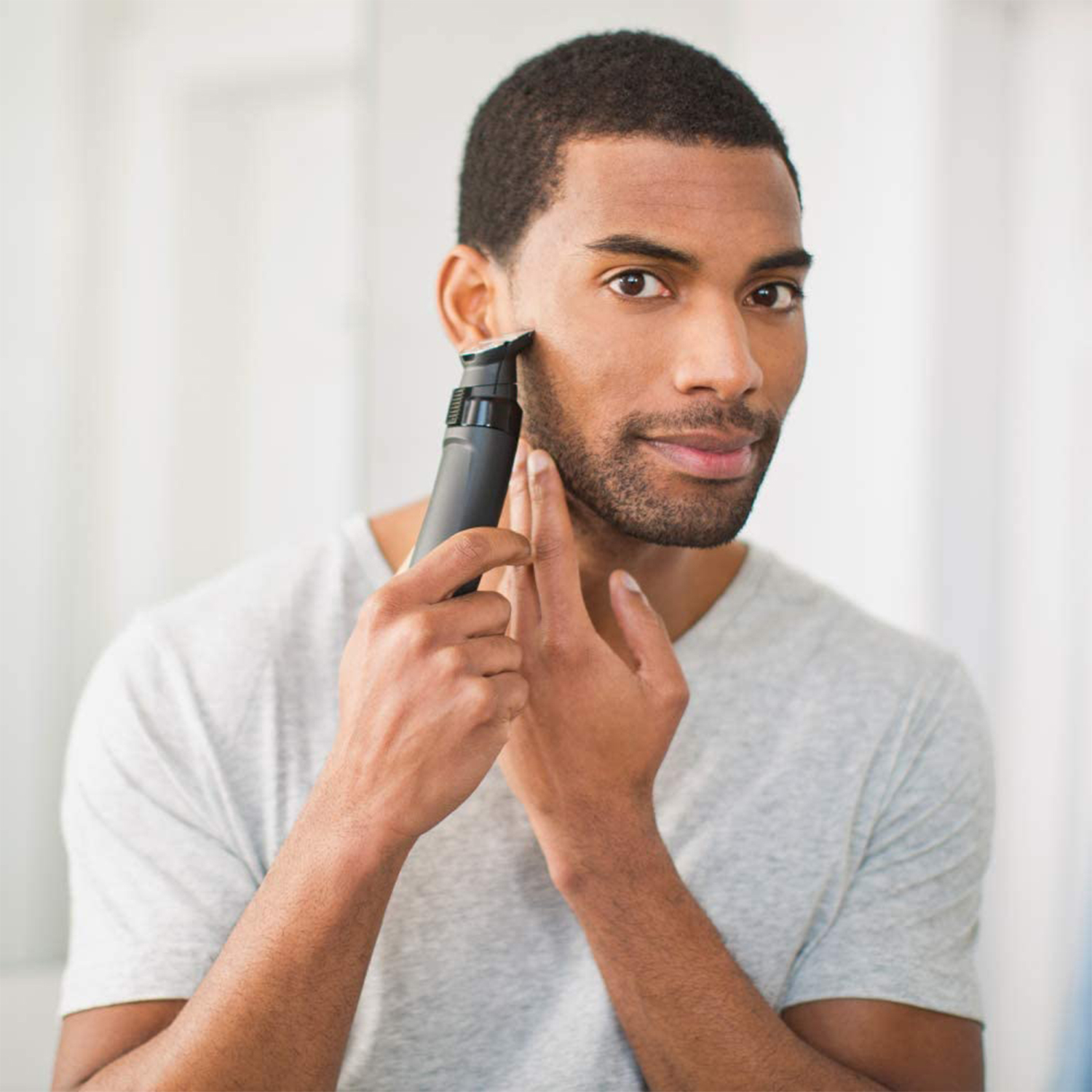 Uomo che taglia la barba con un trimmer elettrico nero.