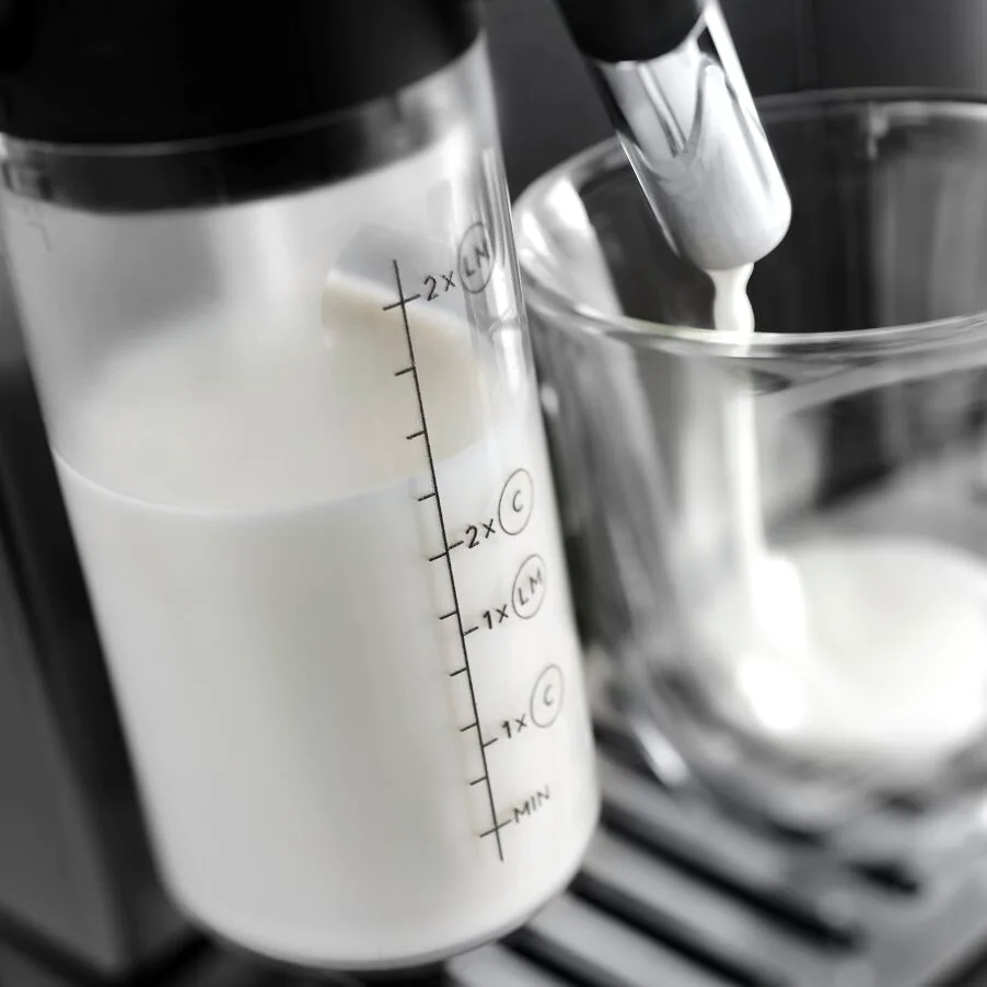 A milk container with measurements, milk pouring into a clear glass.