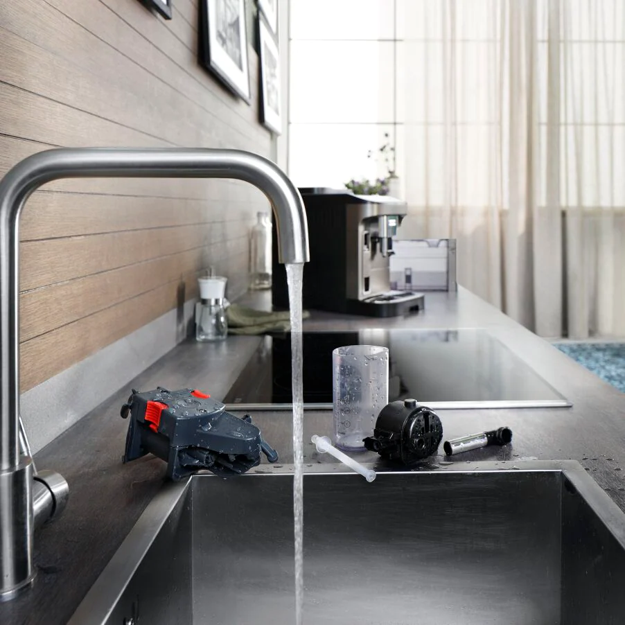 Kitchen scene: Water flowing from a faucet into a sink, with accessories and appliances.