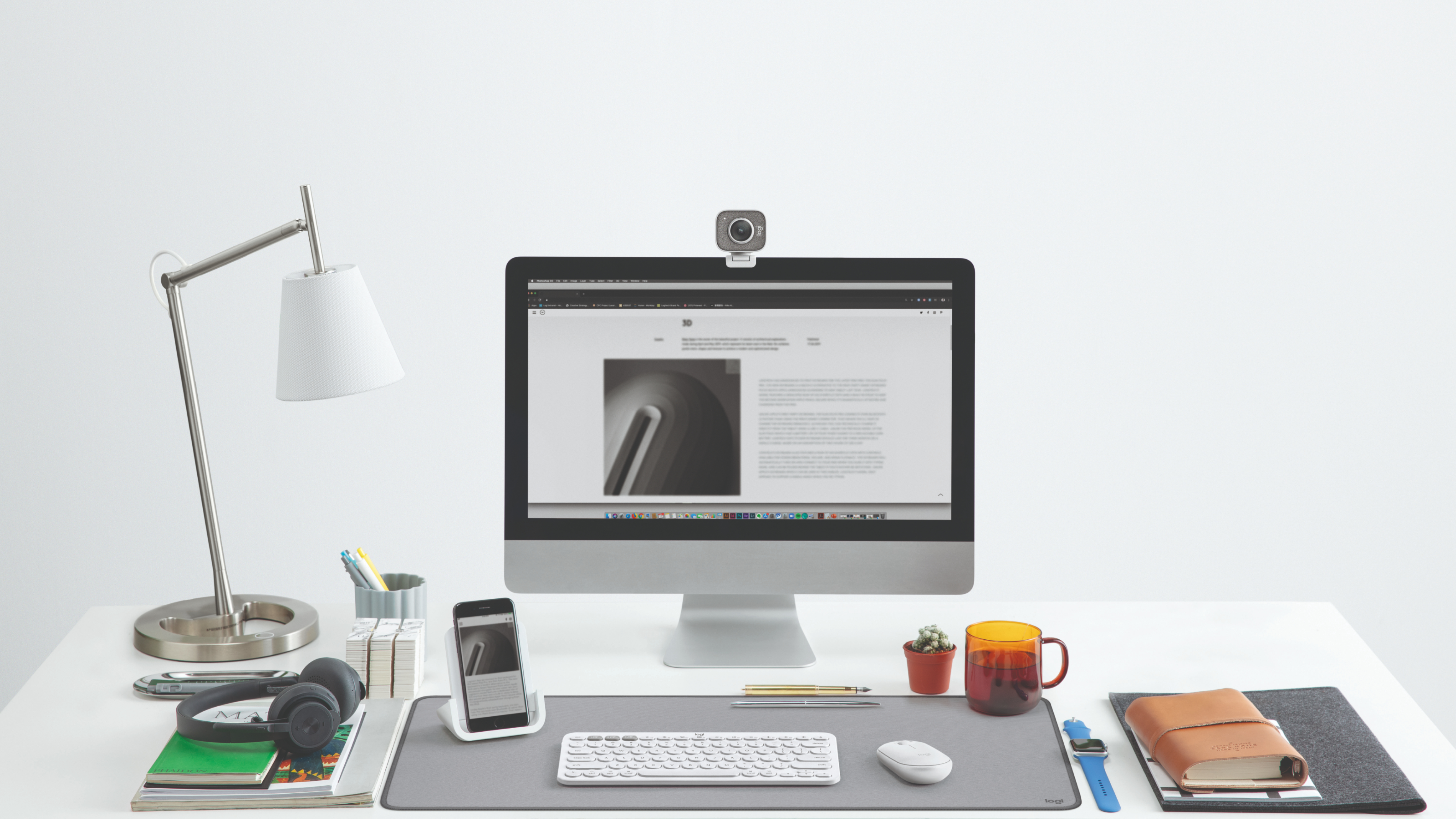 Une configuration de bureau avec un moniteur, une webcam, une lampe, un casque et d'autres articles.
