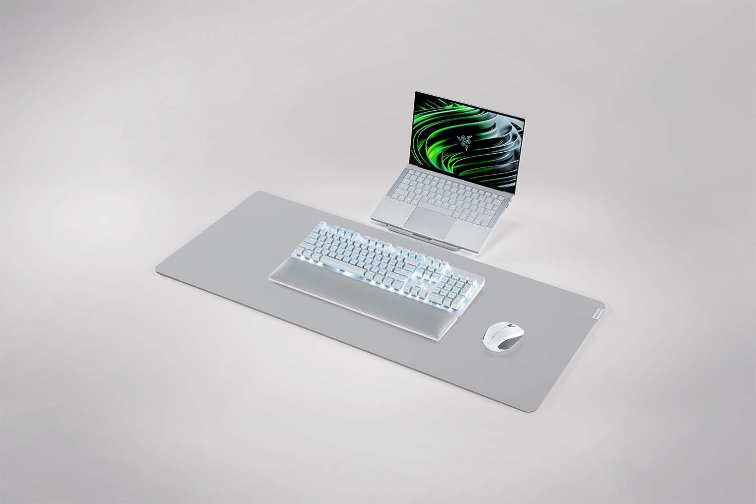 Laptop, Tastatur und Maus auf einer grauen Schreibtischunterlage, alles in hellgrau.