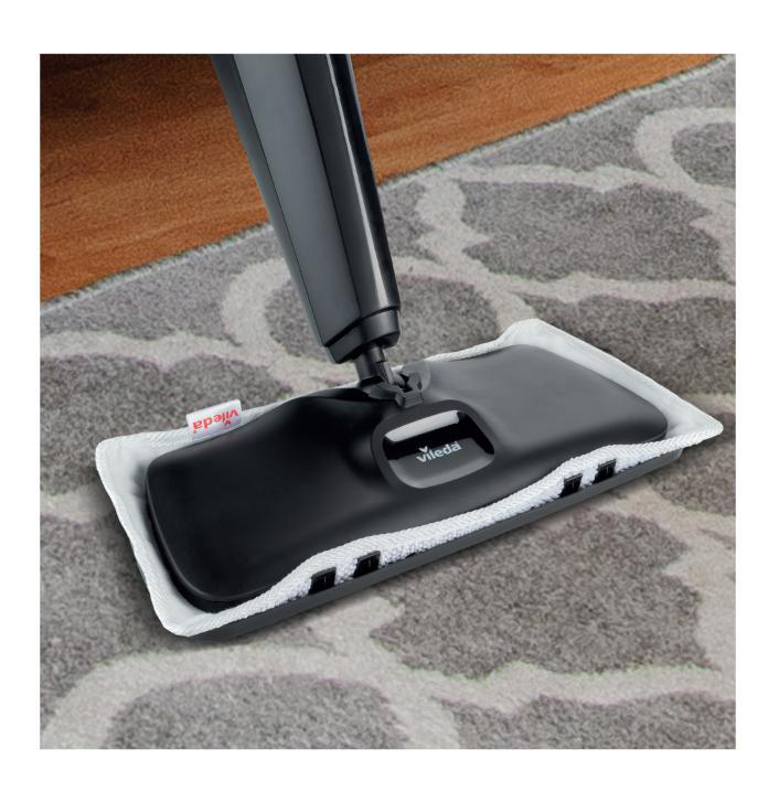 Schwarz-weißer Dampfmopp mit weißem Reinigungspad auf einem gemusterten Teppich.