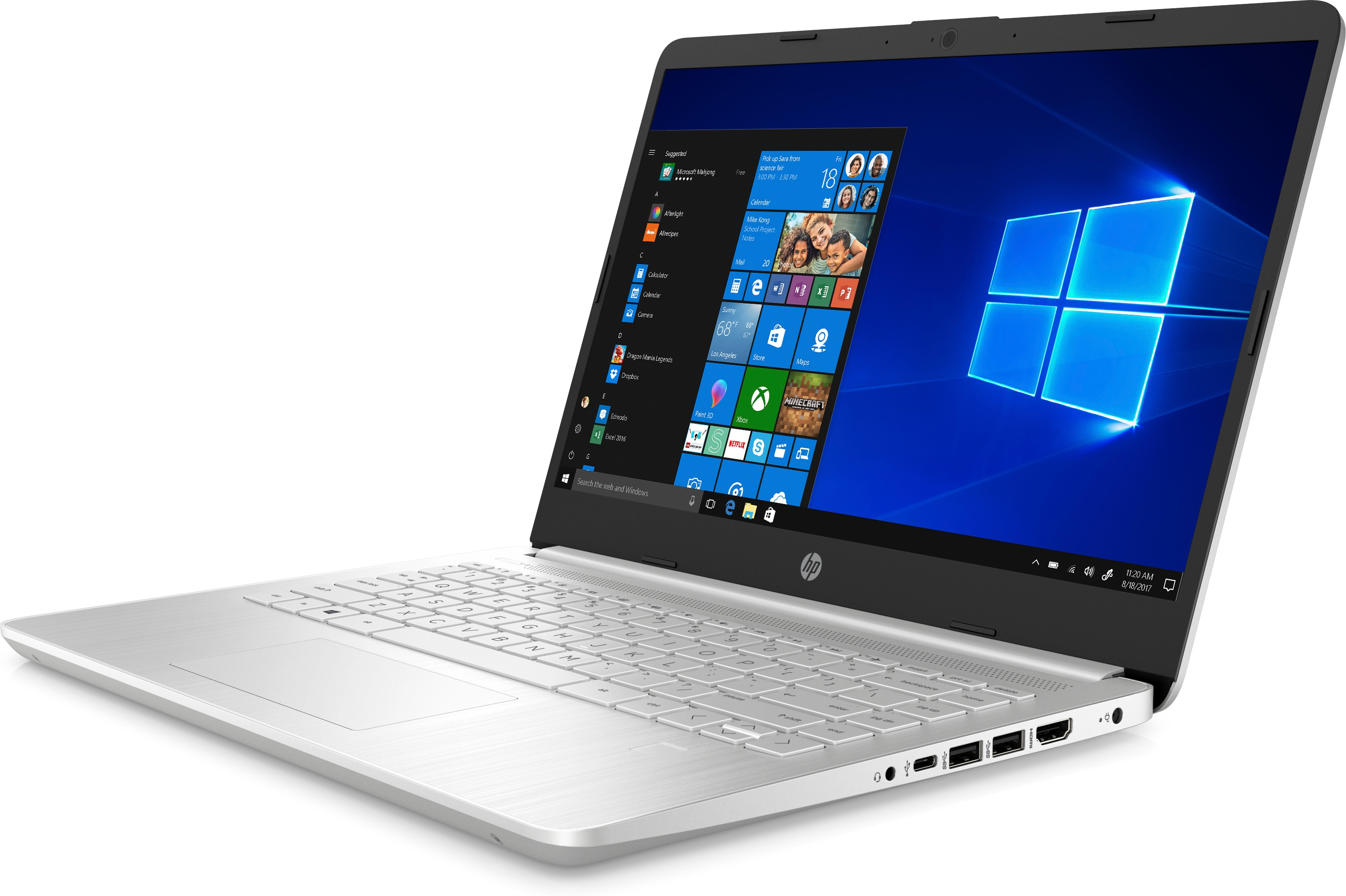 Una computadora portátil plateada está abierta sobre una superficie blanca, mostrando un escritorio de Windows 10. La pantalla es brillante.