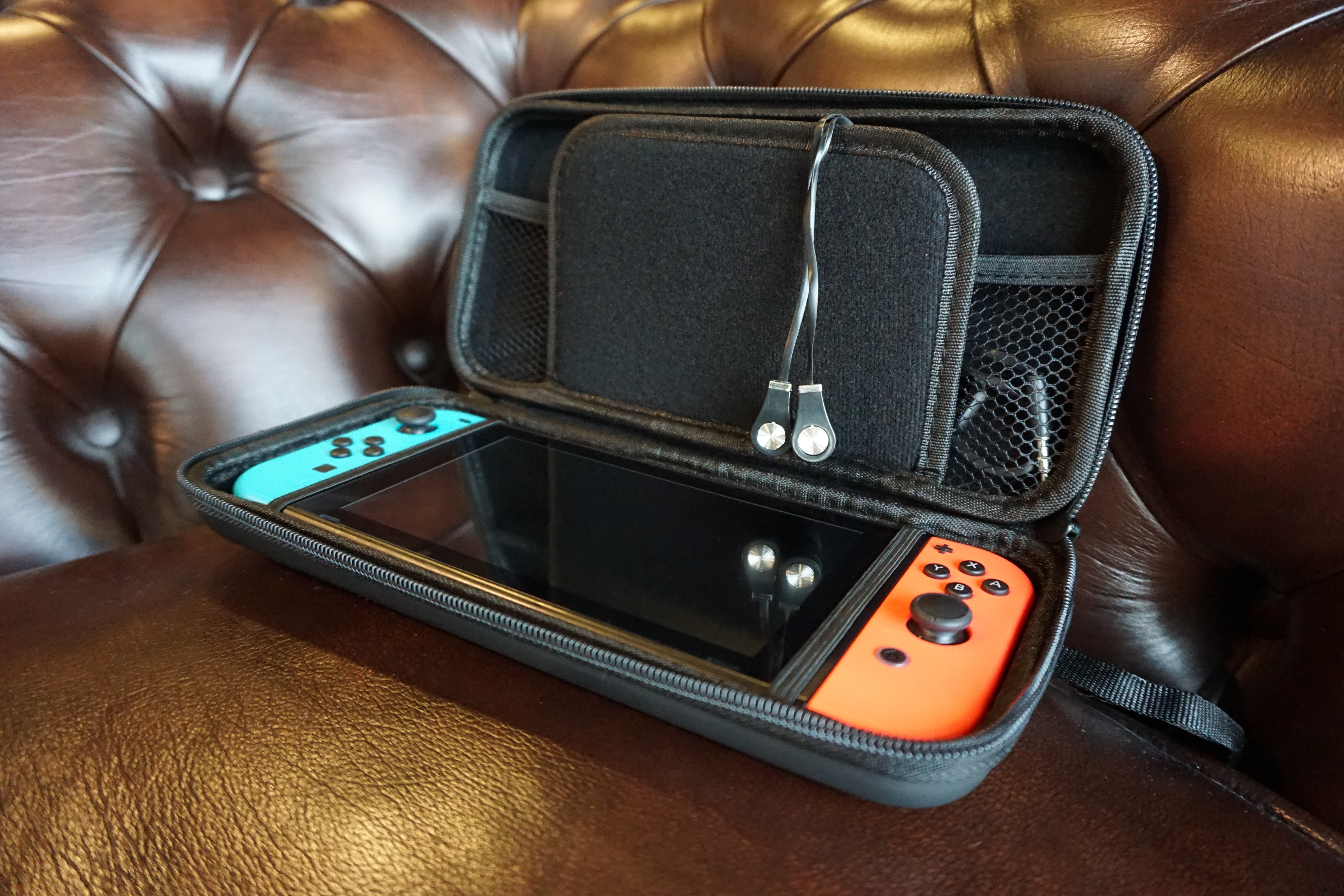 Open black case with a Nintendo Switch, controllers, and headphones.  The case is on leather.