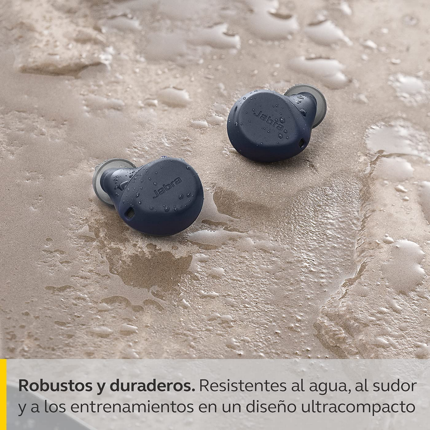 Dos auriculares azul oscuro sobre arena, el logo de Jabra es visible.