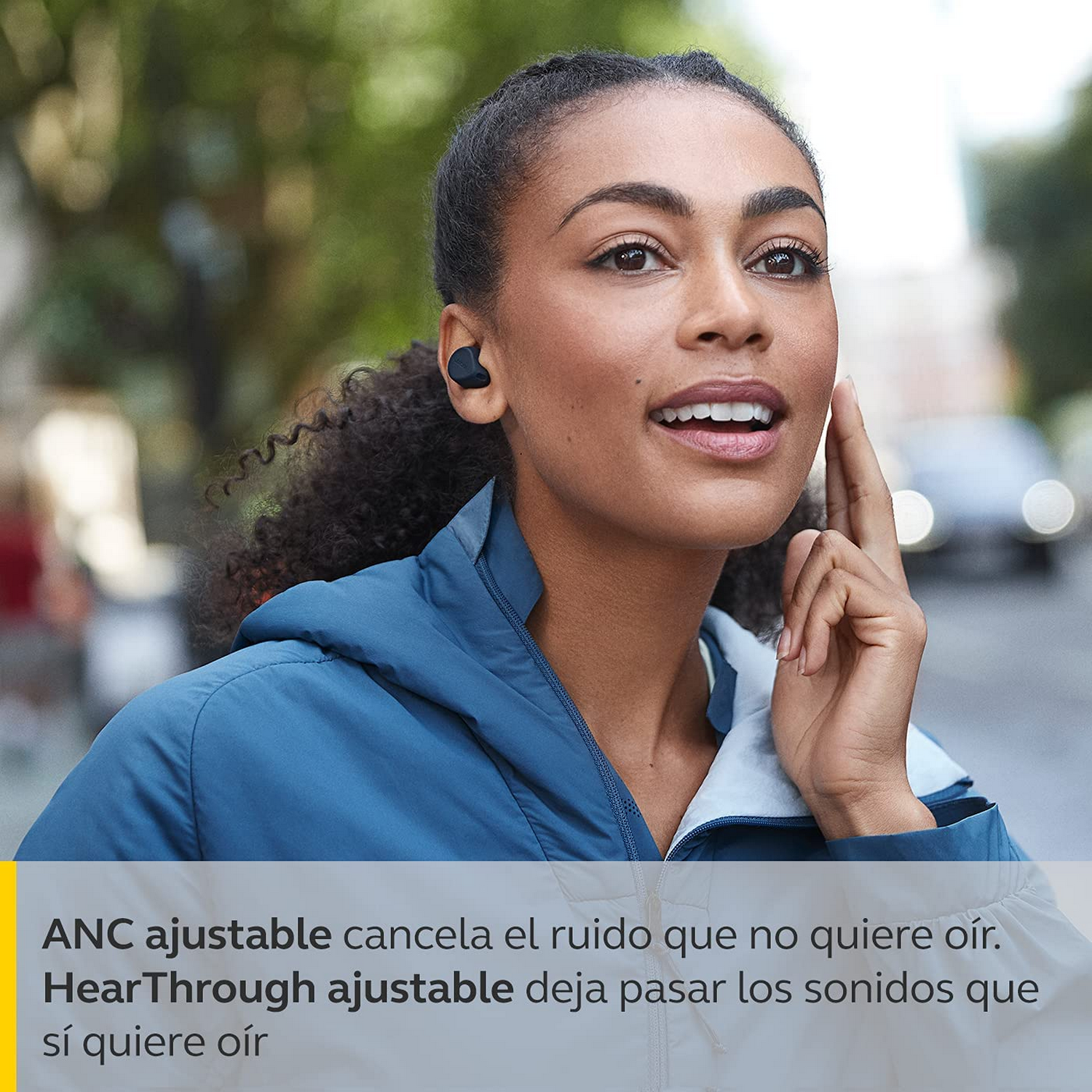 Una mujer con una chaqueta azul lleva auriculares negros. El texto dice HearThrough y ANC.