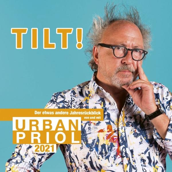 Ein Mann mit Brille und stacheligem Haar vor einem bunten Hintergrund mit Text.
