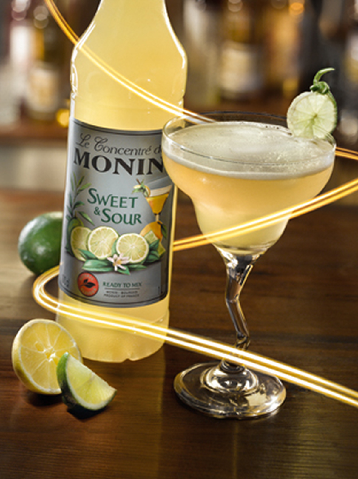 Monin Sweet & Sour Flasche mit Cocktail im Margaritaglas und Limette.