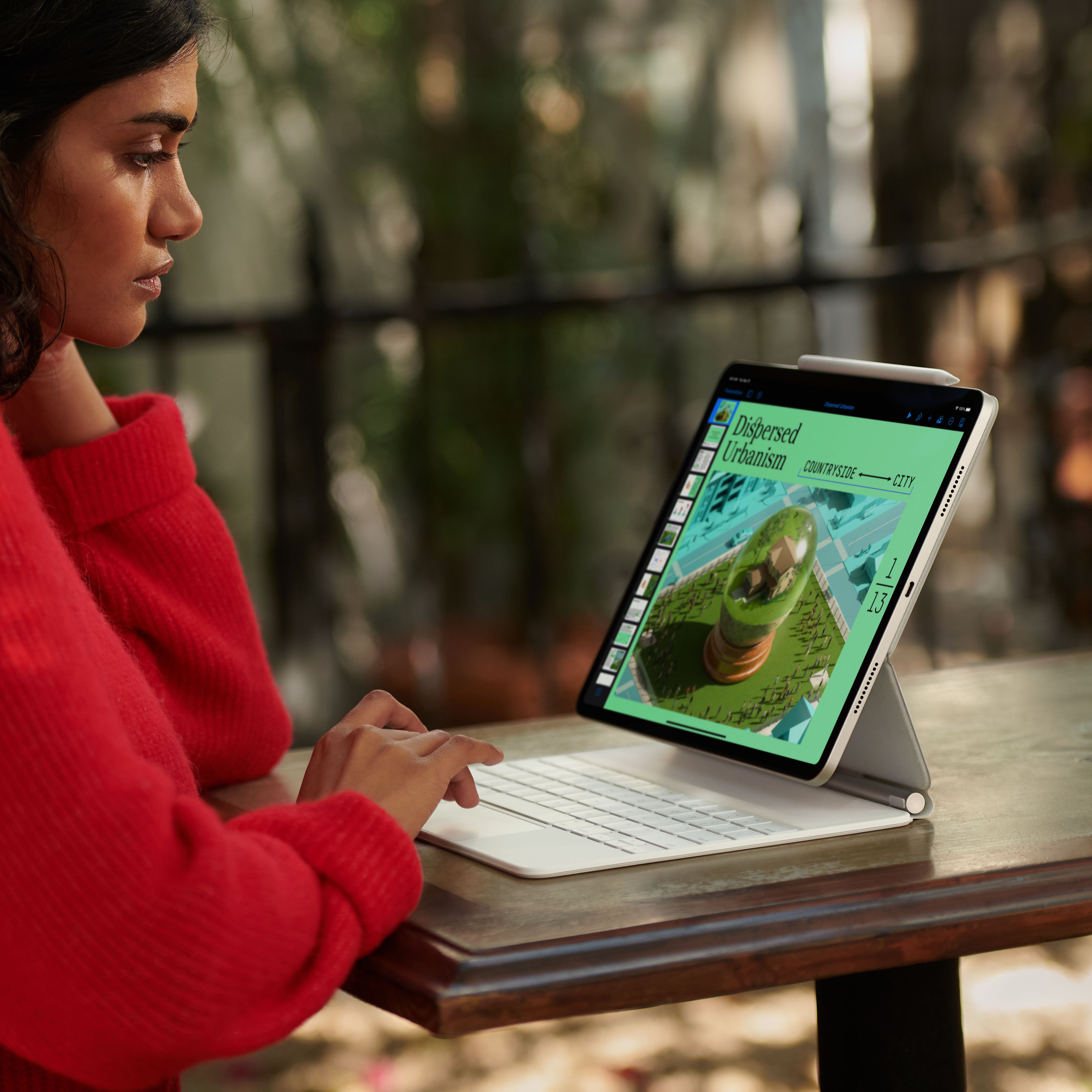 Een vrouw die een tablet met een toetsenbord gebruikt, waarbij het scherm een ​​magazinelay-out weergeeft.