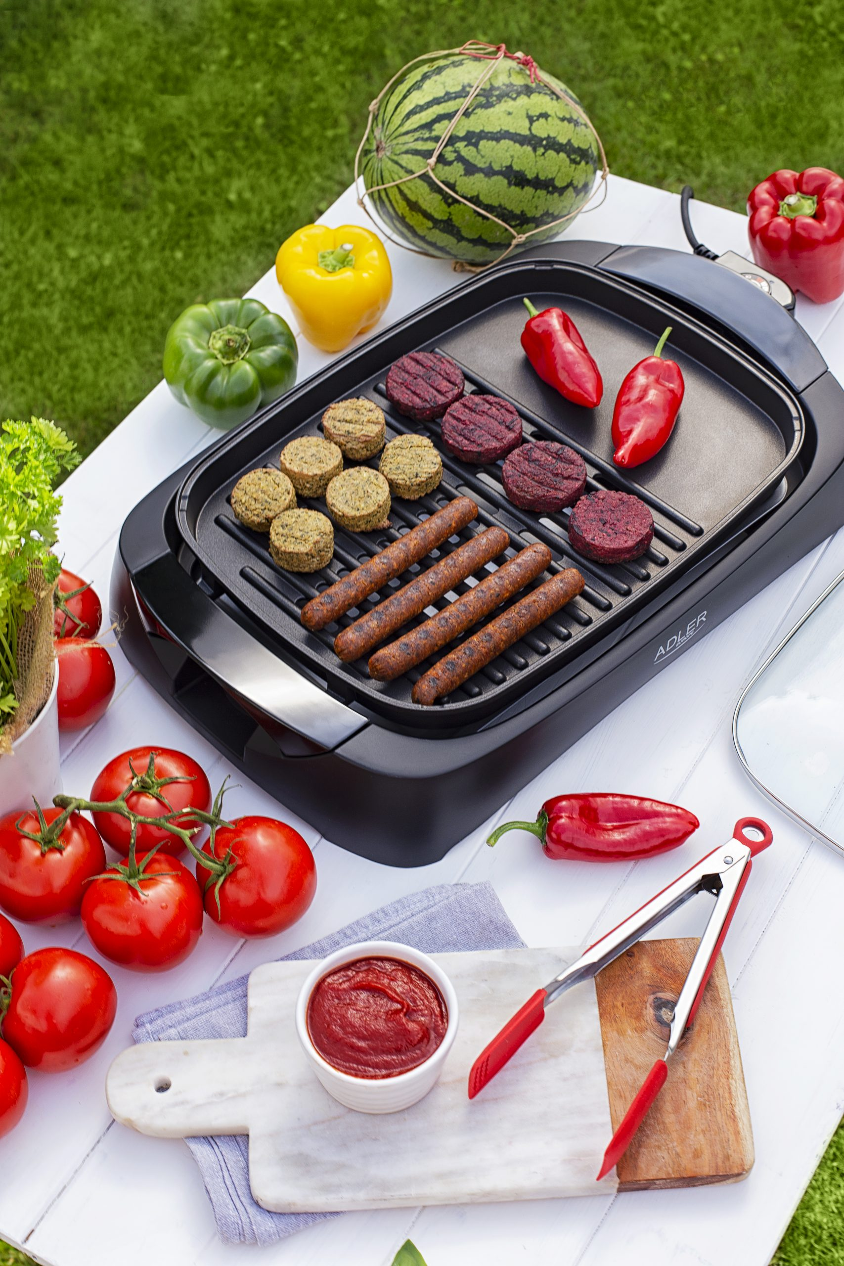 Szabadtéri grillezős jelenet étellel a grillen és közeli hozzávalókkal.