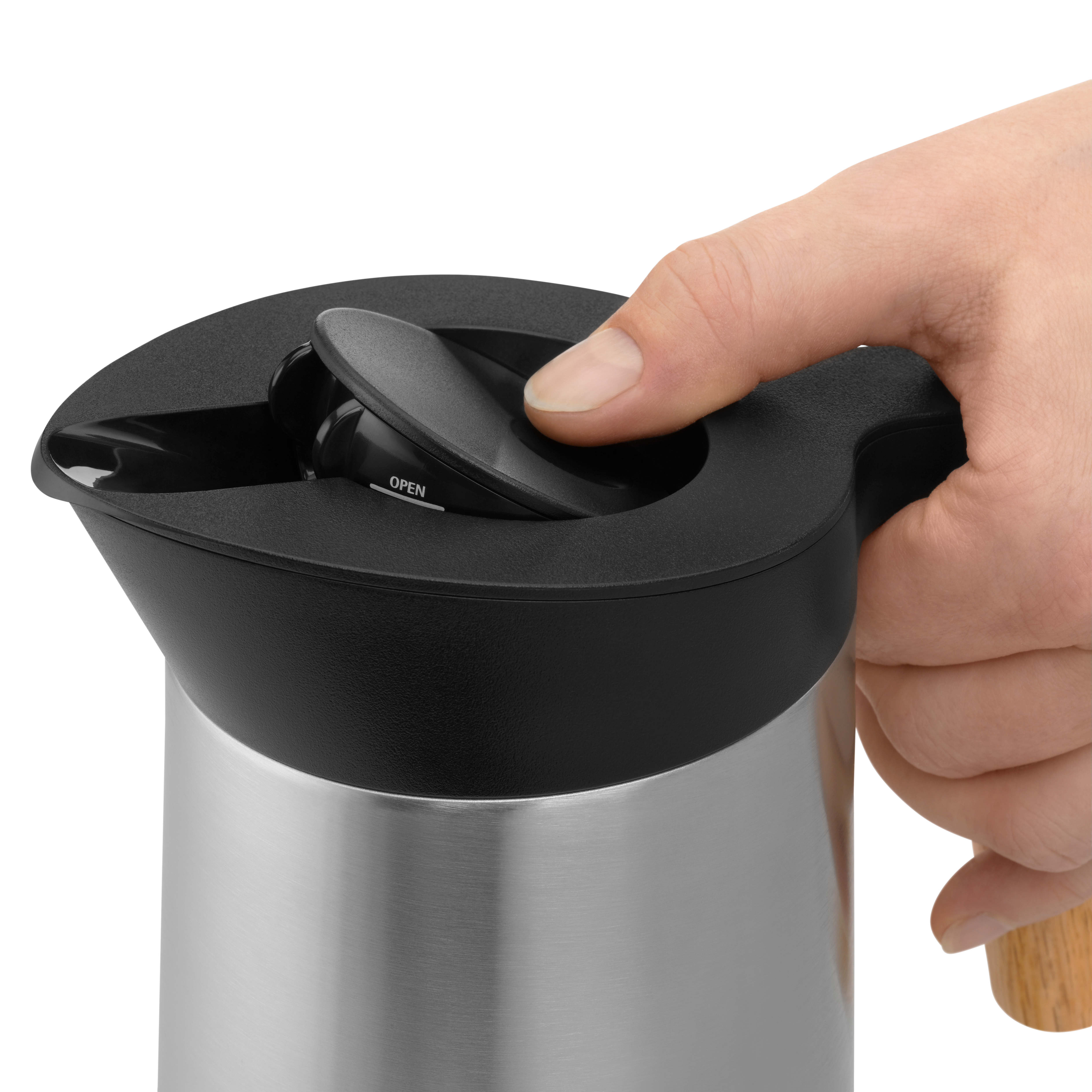 Hand öffnet den schwarzen Deckel einer silbernen, isolierten Edelstahlkanne.