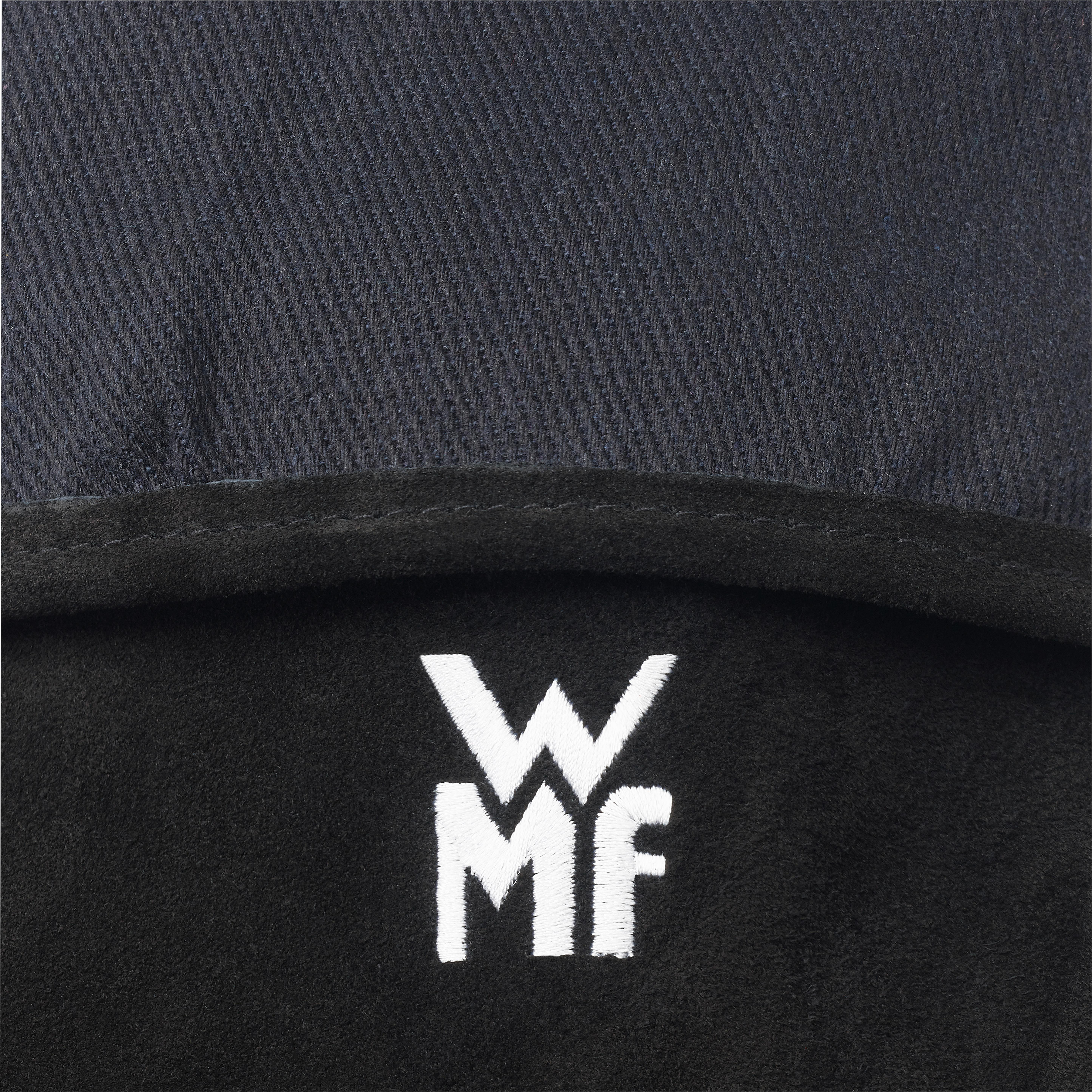 Nahaufnahme, eine schwarze Kochmütze mit dem gestickten WMF-Logo.