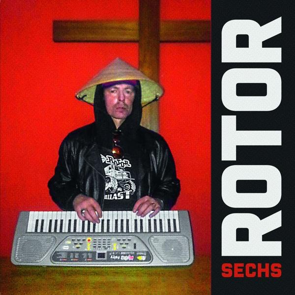 Albumcover. Mann mit konischem Hut spielt Keyboard. Roter Hintergrund, Kreuz und das Wort SECHS.