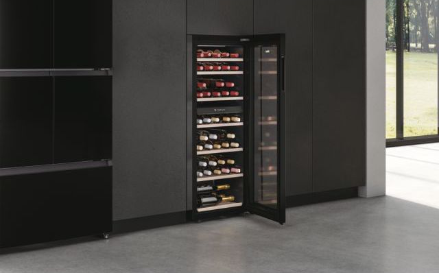Cantinetta con porta aperta, che mostra bottiglie di vino rosso e bianco, contro mobili scuri.