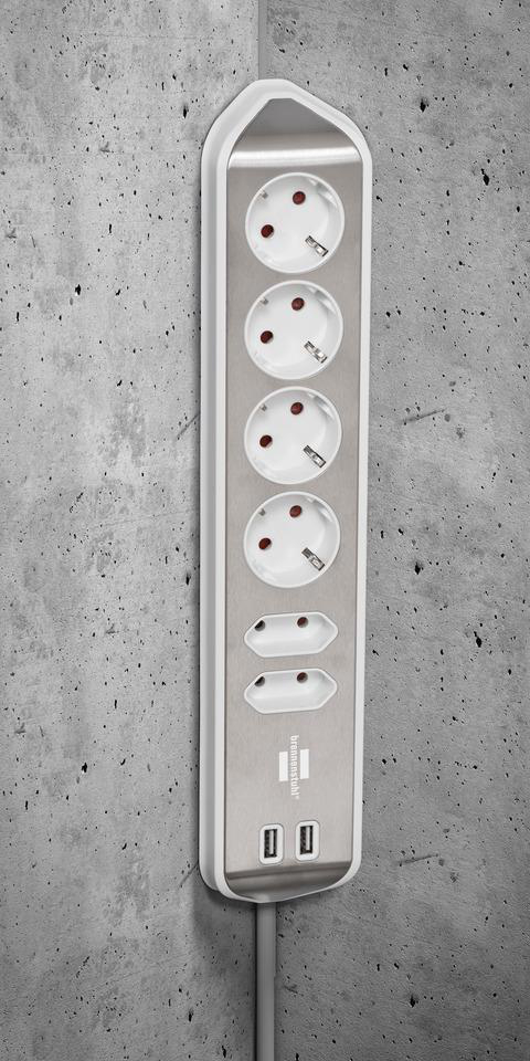 Steckdosenleiste an einer Wand montiert. Sie hat mehrere Steckdosen und USB-Anschlüsse.