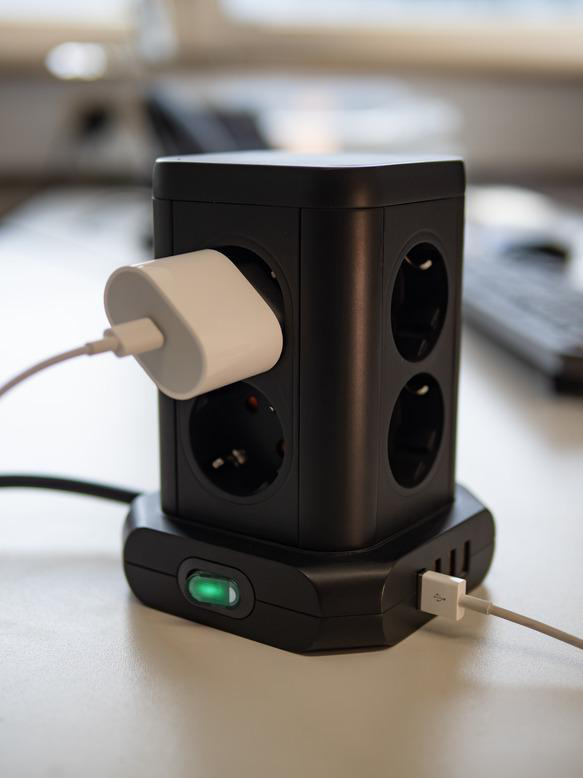Schwarze Steckdosenleiste mit weißem Stecker.