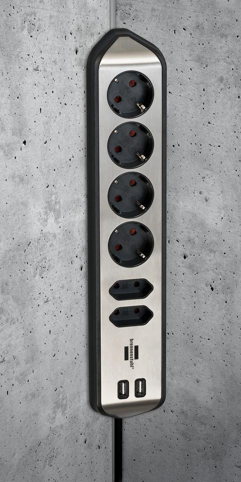 Eine vertikale Steckdosenleiste mit mehreren Steckdosen und USB-Anschlüssen vor einer strukturierten grauen Wand.