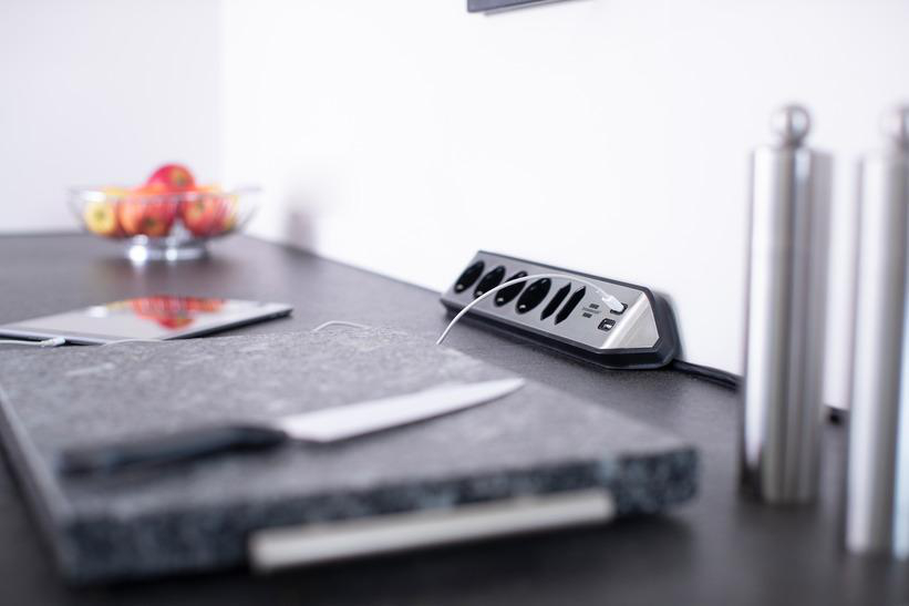 Eine moderne Küche mit Arbeitsplatte und Steckdose mit USB-Anschlüssen, einem Schneidebrett und einem Messer.