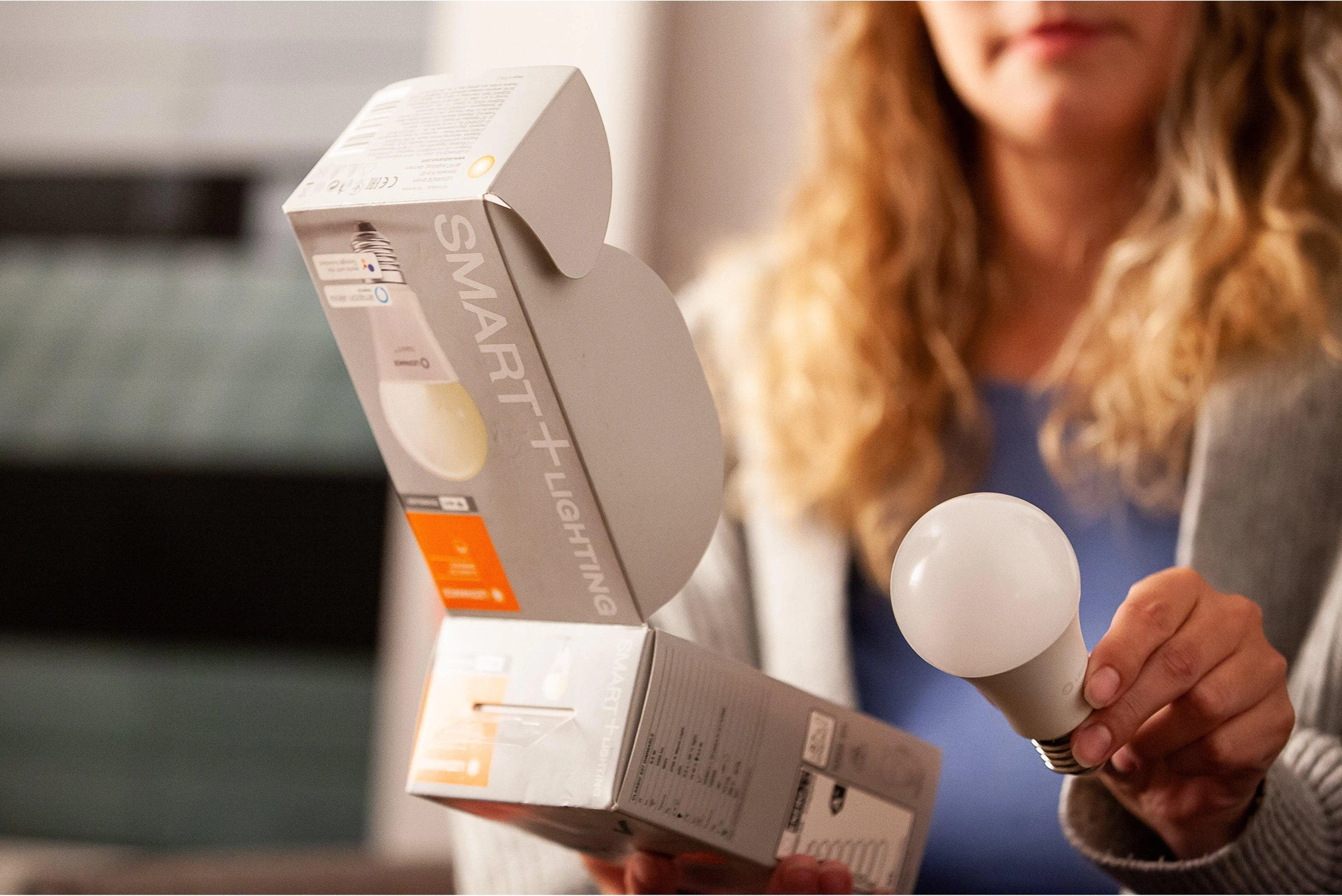 Frau hält eine Smart-Lighting-Box und eine Glühbirne.