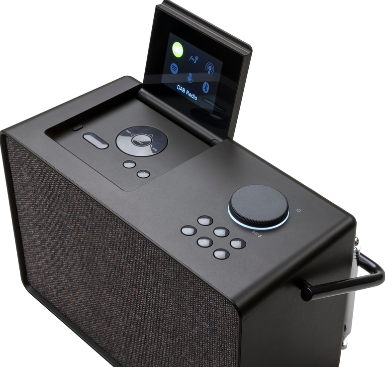 Radio DAB noire avec un écran, des boutons et une poignée, sur une surface blanche.