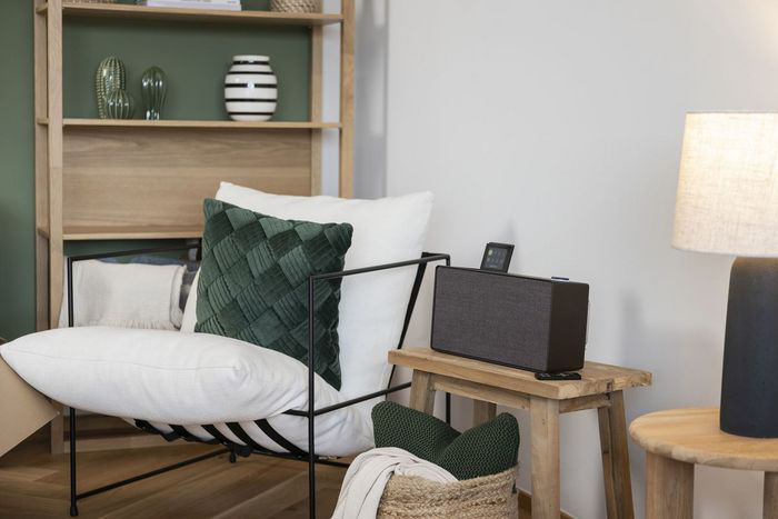 Salon avec enceinte sur une table, fauteuil et objets décoratifs.