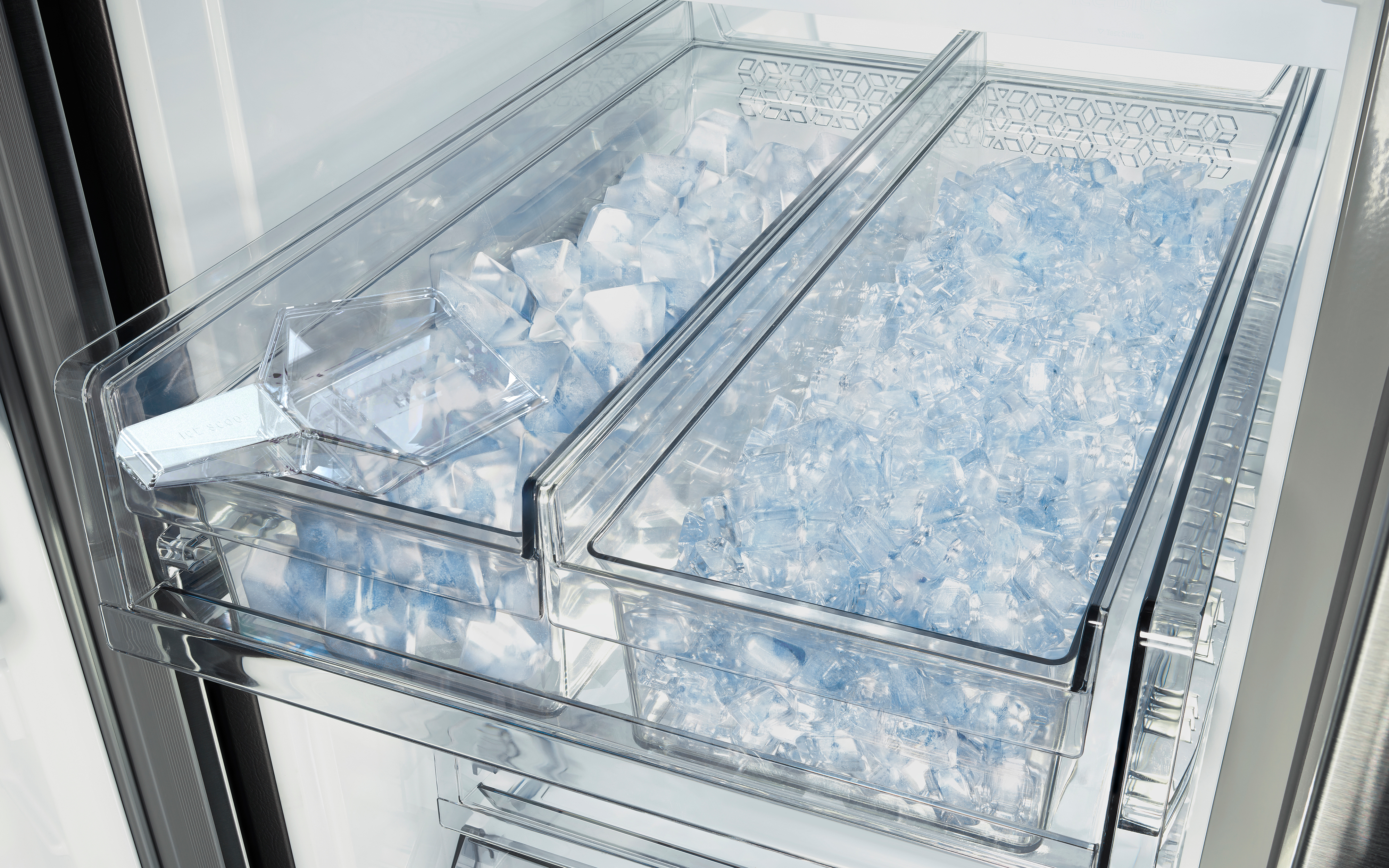 Kühlschrankinnenraum mit Eiswürfelschalen, gefüllt mit Eiswürfeln, und einem Eiswürfelbehälter.