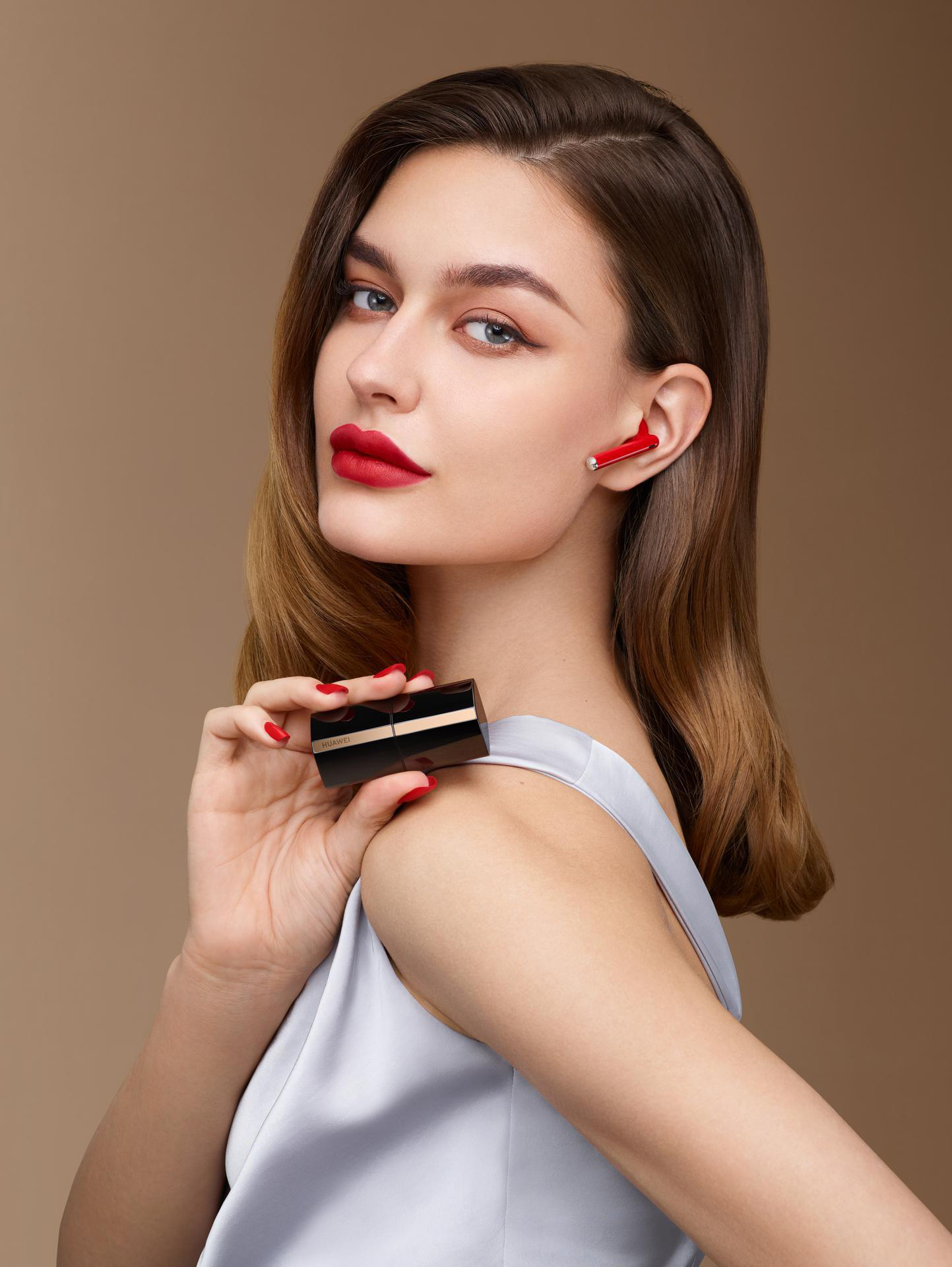 Eine Frau mit rotem Lippenstift und Ohrhörern, die einen Lippenstift hält.