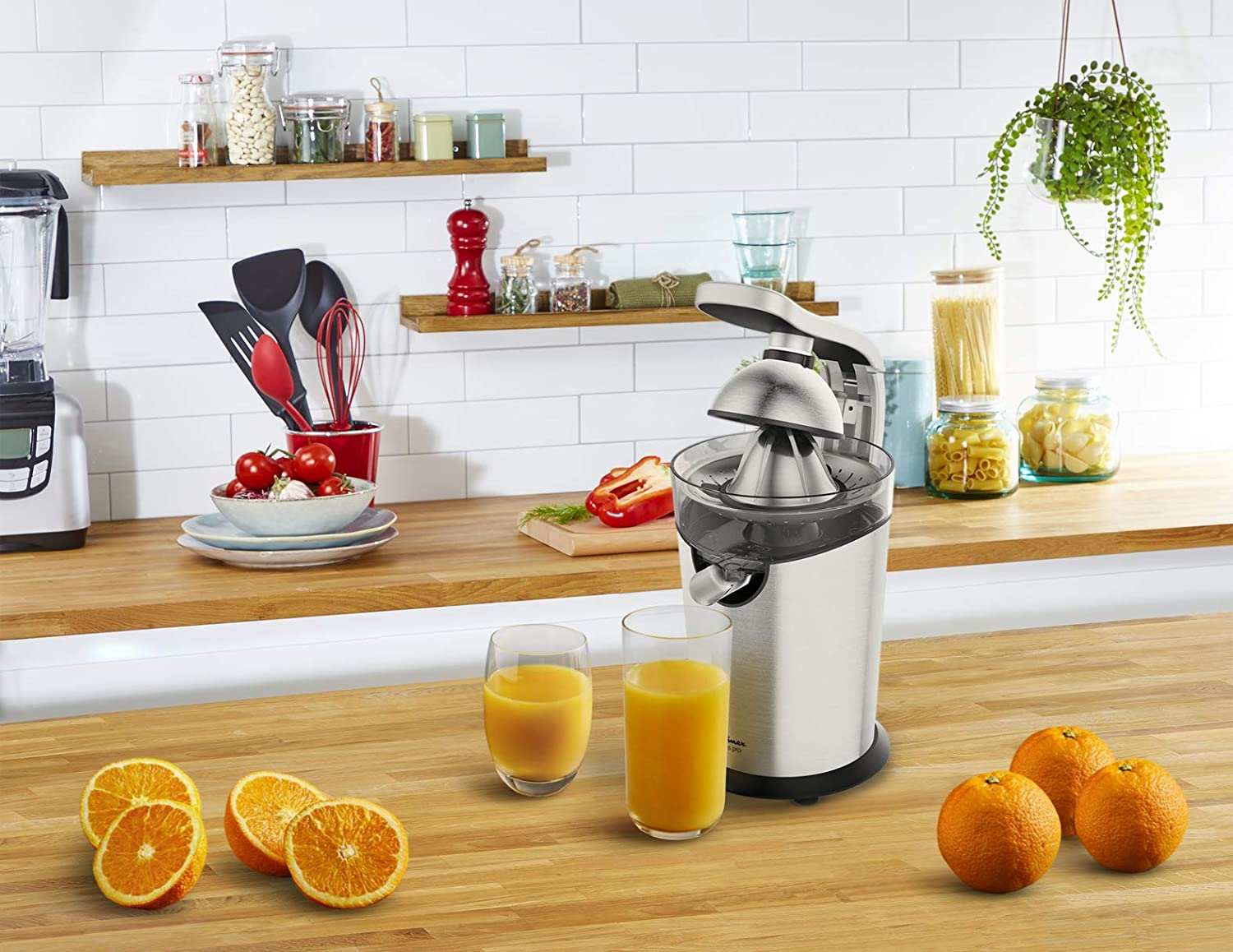 A juicer with oranges and two glasses of juice.