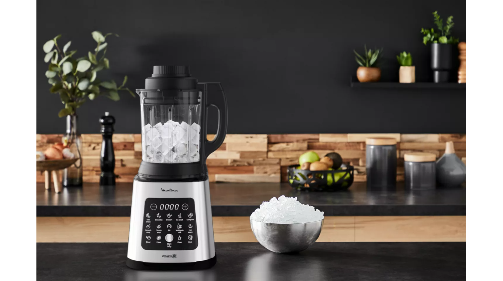Blender with ice in container, ice bowl, and kitchen background.
