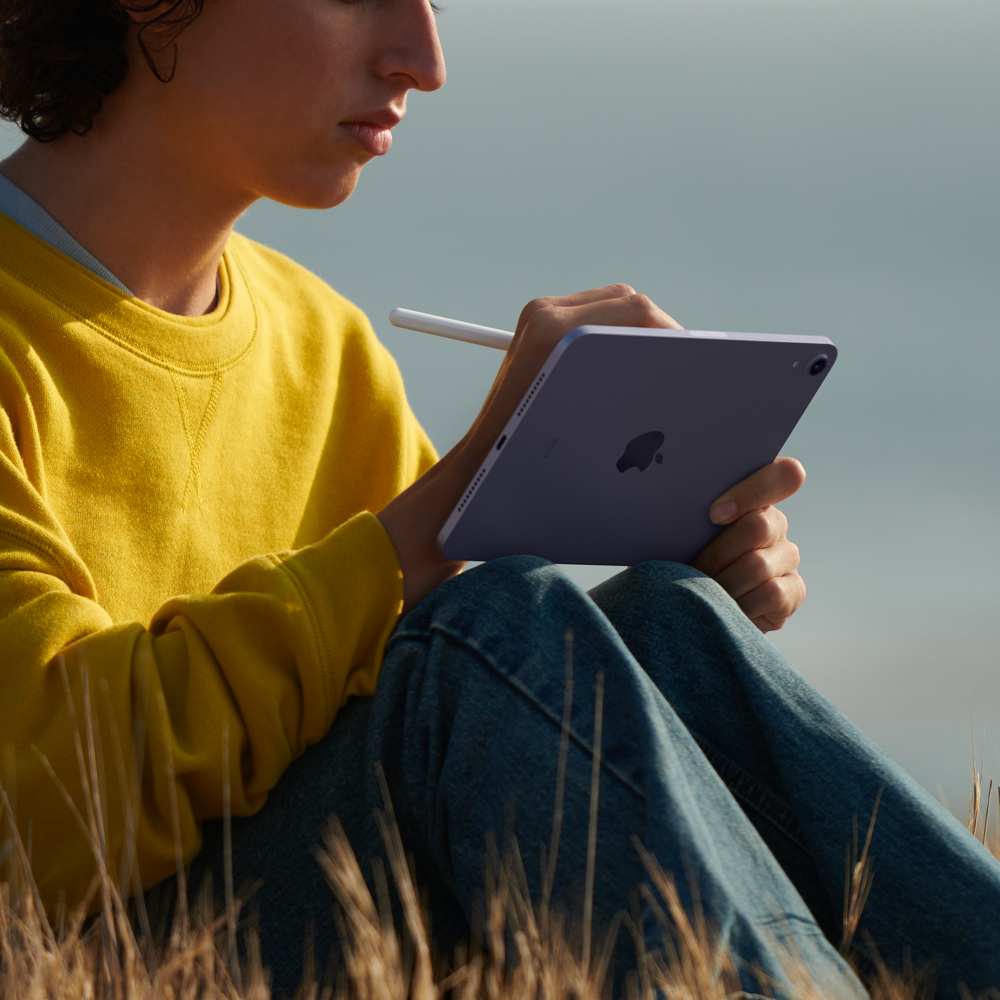 Açık havada, beyaz bir kalemle mor bir tablet üzerine çizim yapan kişi.