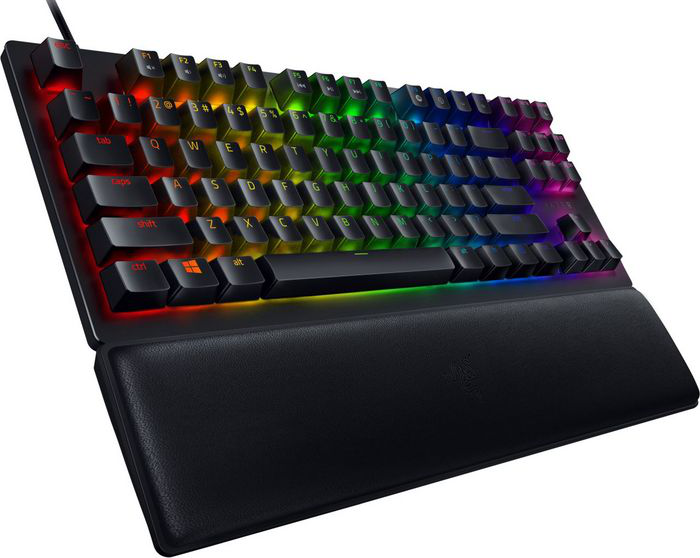 Schwarze Tastatur mit Regenbogen-Tasten und Handgelenkauflage. Schwarze Tasten und ein Kabel sind sichtbar.