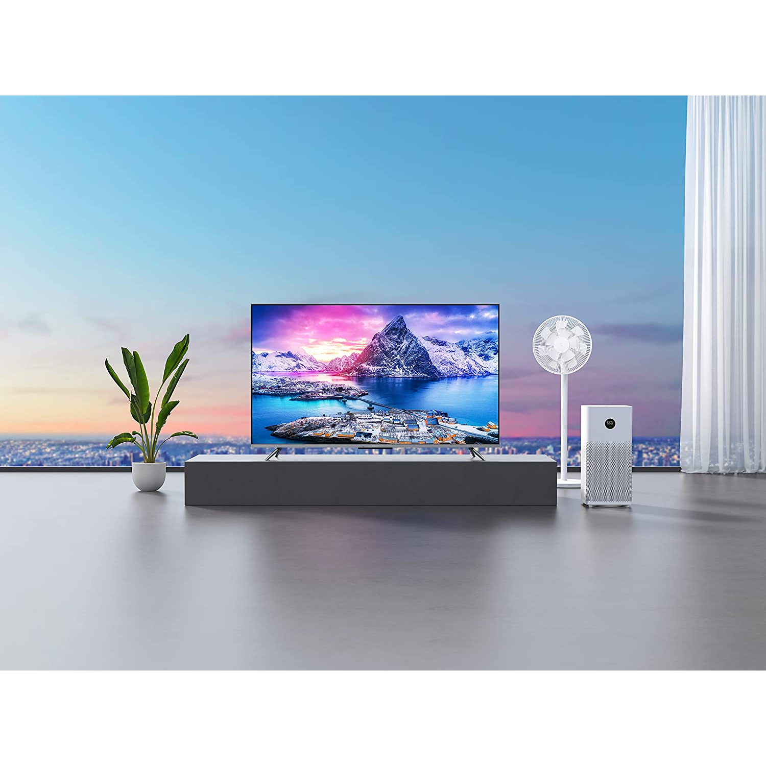 Sala de estar con un televisor grande mostrando una escena de montaña. Planta, purificador de aire y ventilador presentes.
