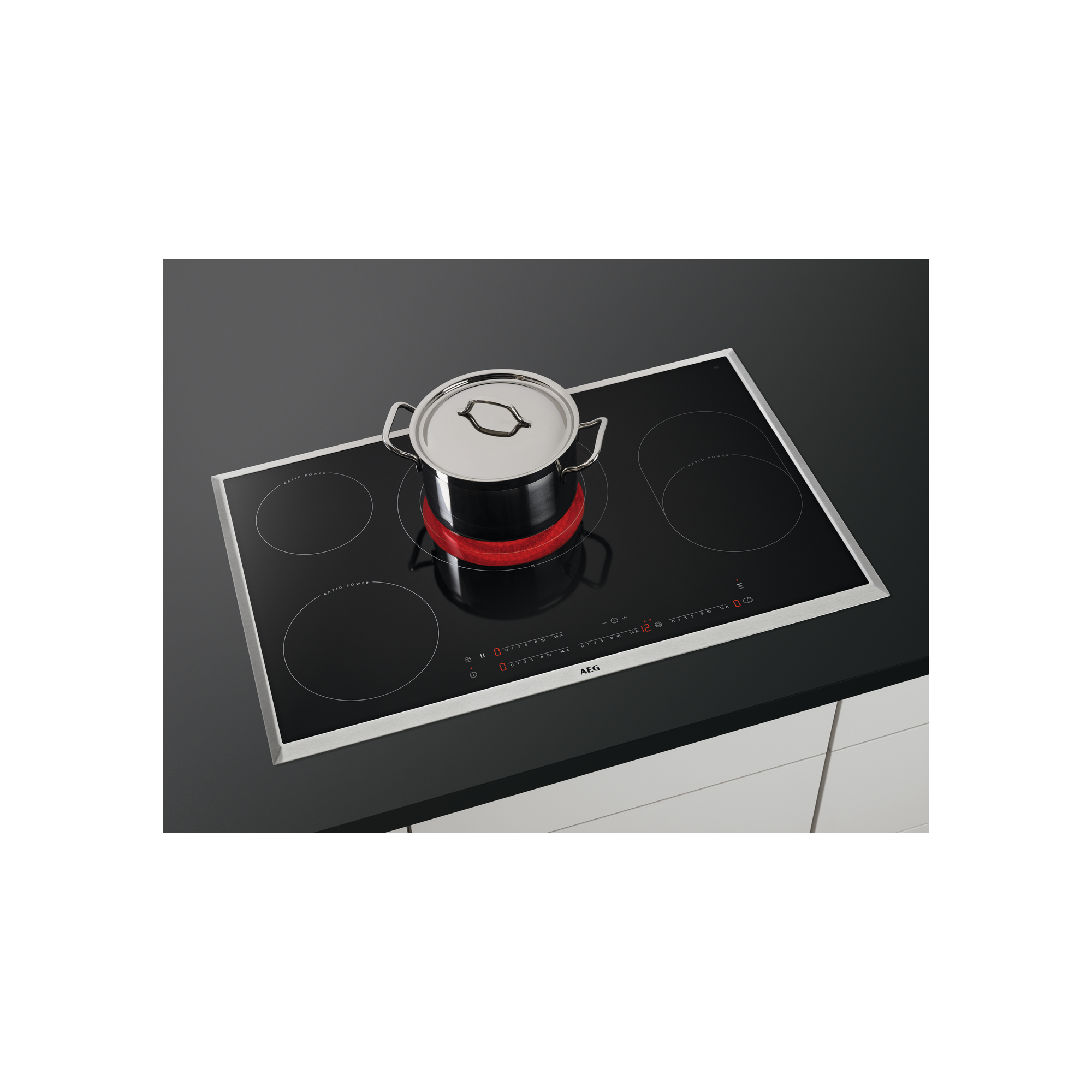 Une table de cuisson à induction avec une casserole sur un brûleur rouge, surface noire et comptoir blanc.