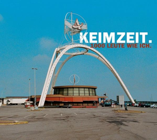 Außenaufnahme eines Gebäudes mit einem Torbogen, Schild mit dem Wort 'Keimzeit' und Text '1000 Leute wie ich'.