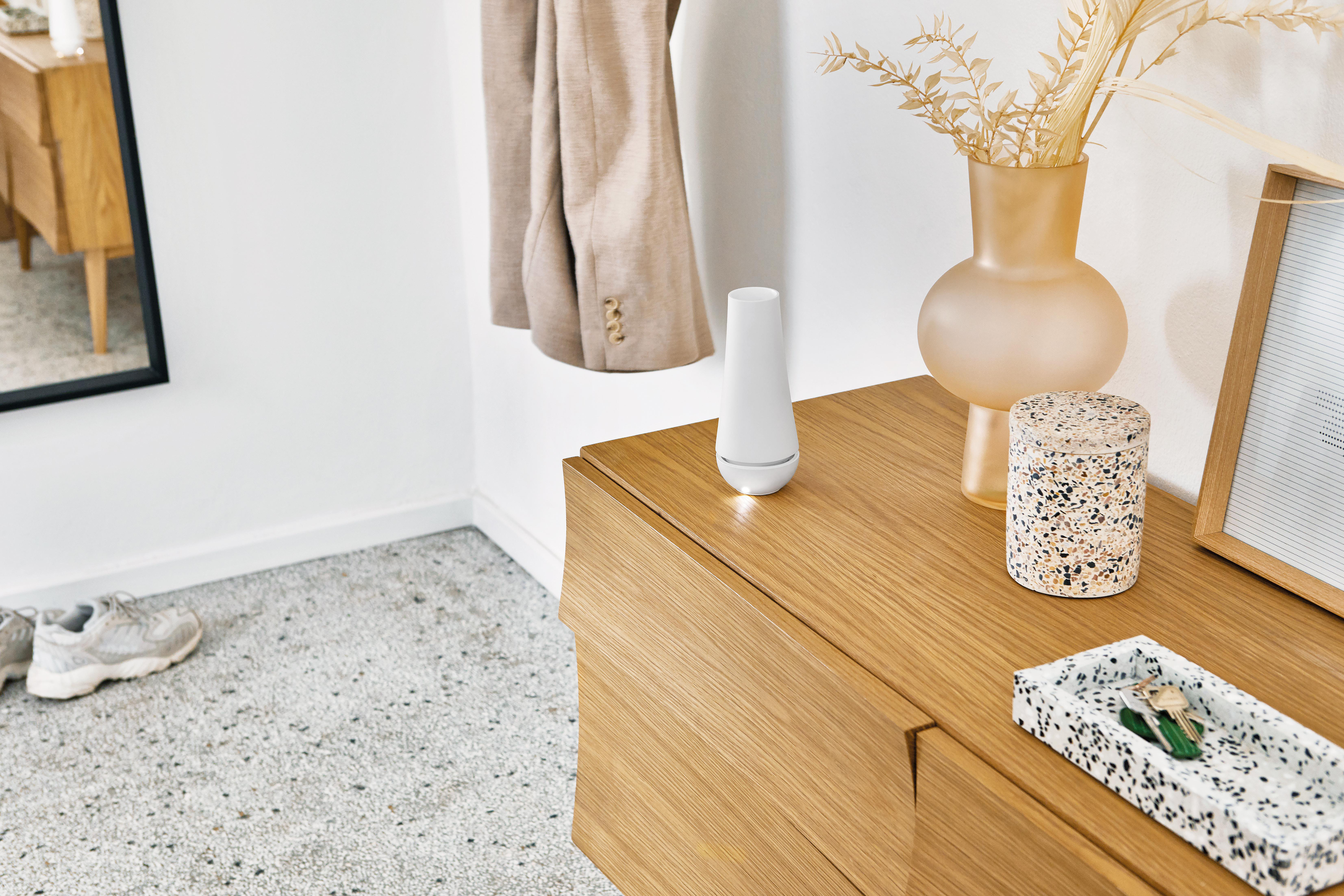Holzschrank mit Gegenständen: weißes Gerät, Vase, dekorative Box und Schlüssel.