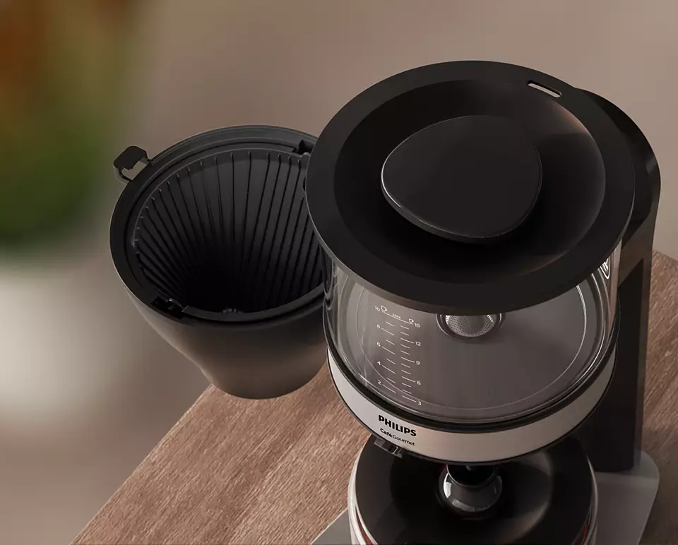 Coffee maker: black design, open lid, glass carafe, wooden surface.
