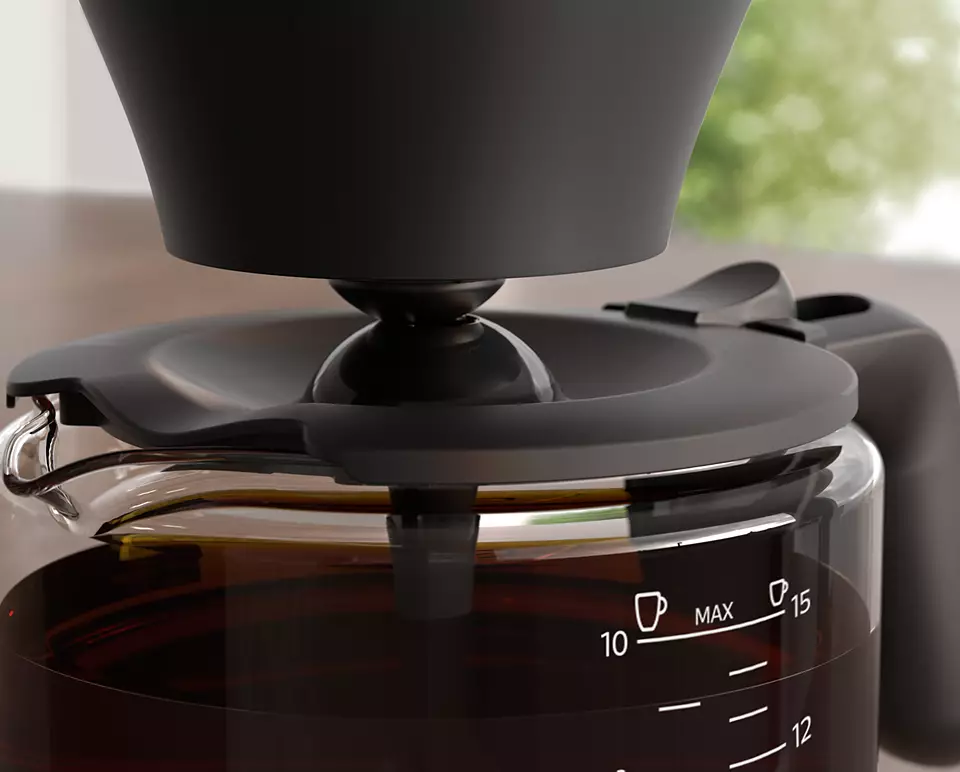 Coffee maker, glass carafe with coffee. Black lid. Close-up, brown liquid.