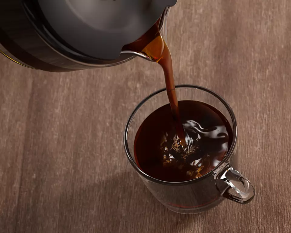 Coffee being poured into a glass mug.
