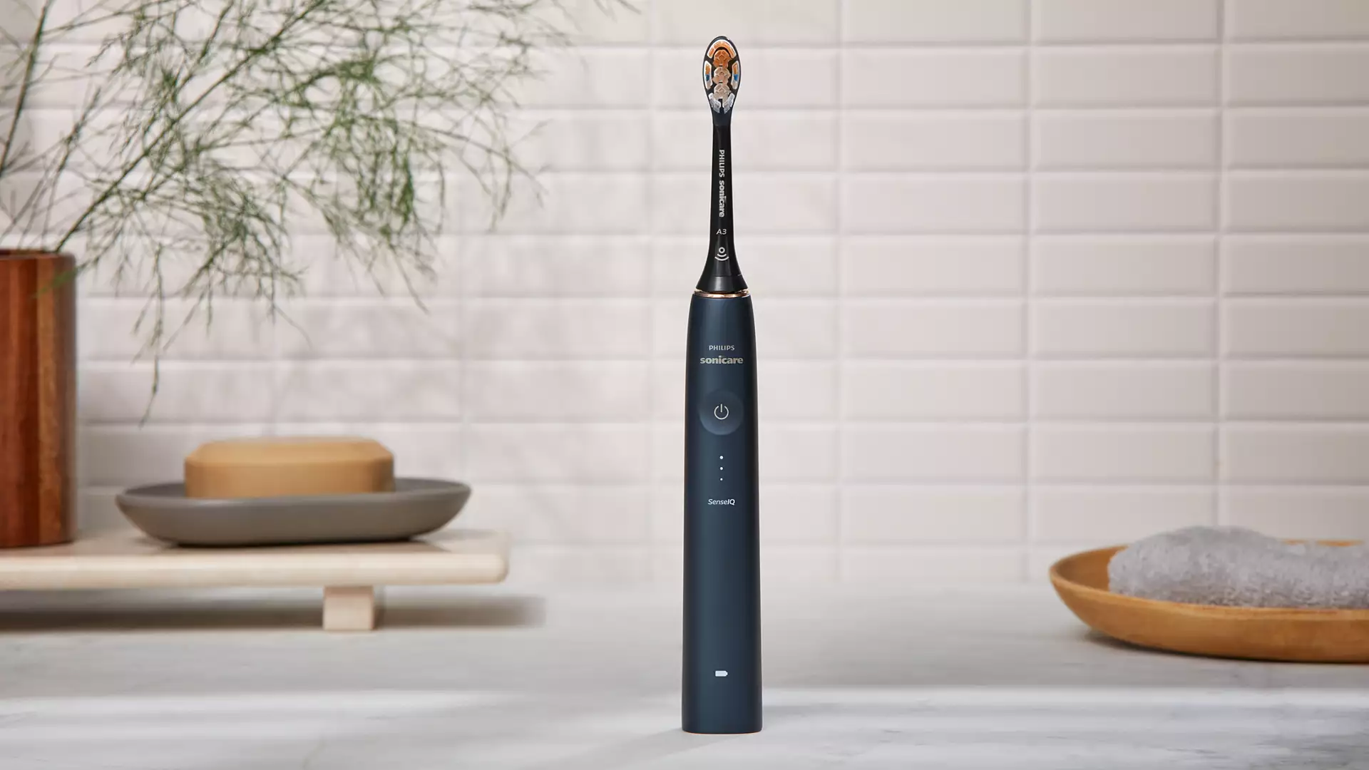 An electric toothbrush on a white surface, with a white tile background.