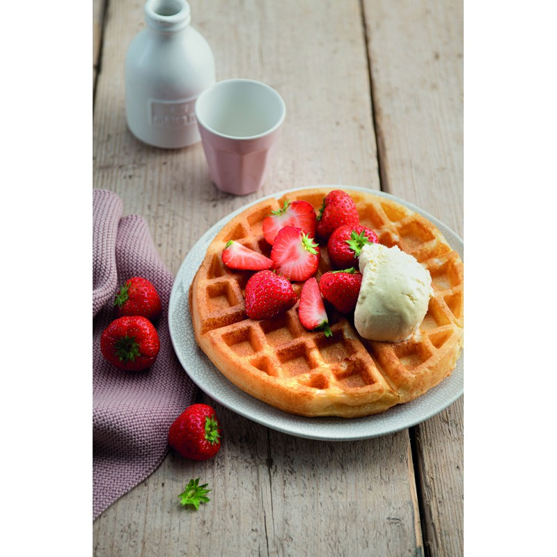 Wafel met aardbeien en ijs op een bord, met een kan en een kopje.