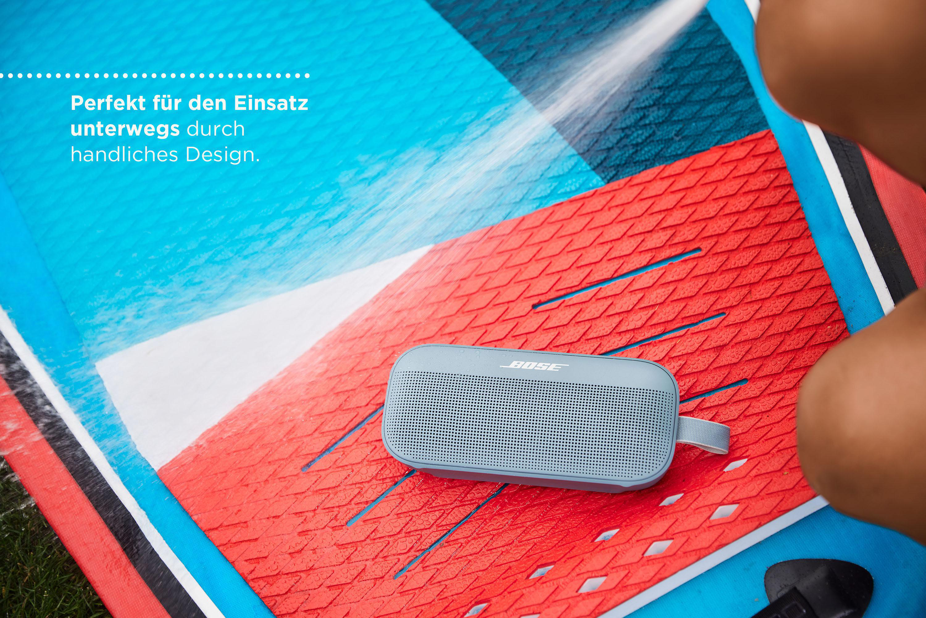 Blauer Lautsprecher auf einem Surfbrett mit rot-blauem Design. Nahaufnahme.
