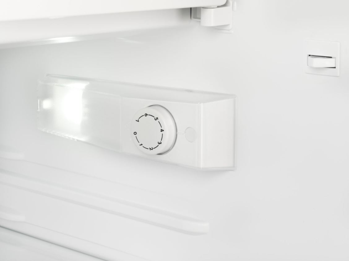 À l'intérieur d'un réfrigérateur blanc, une lumière et un cadran de contrôle de température sont visibles.