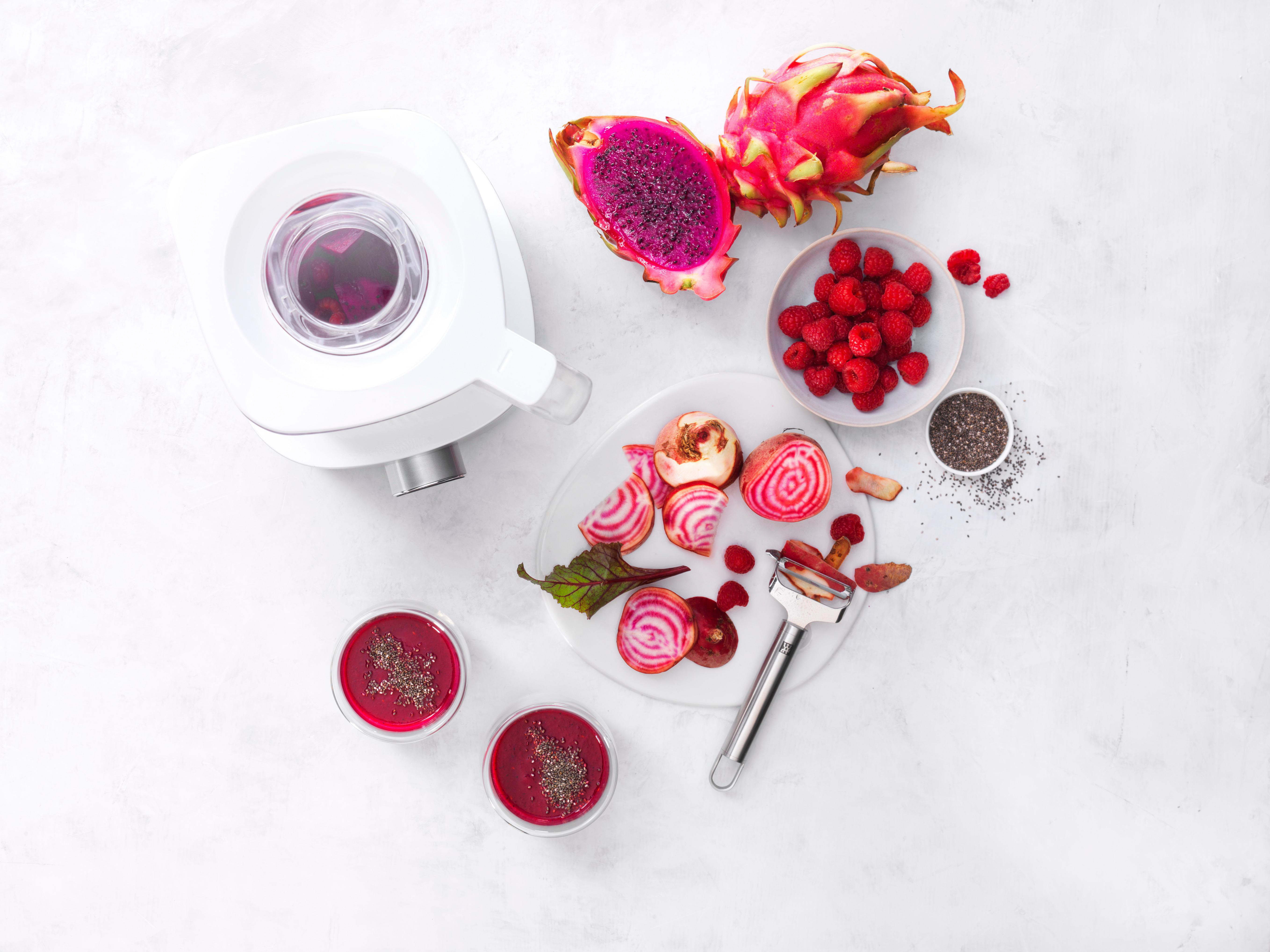 Weißer Mixer mit Zutaten: Drachenfrucht, Himbeeren, Rüben, Chiasamen, Smoothie-Getränke.